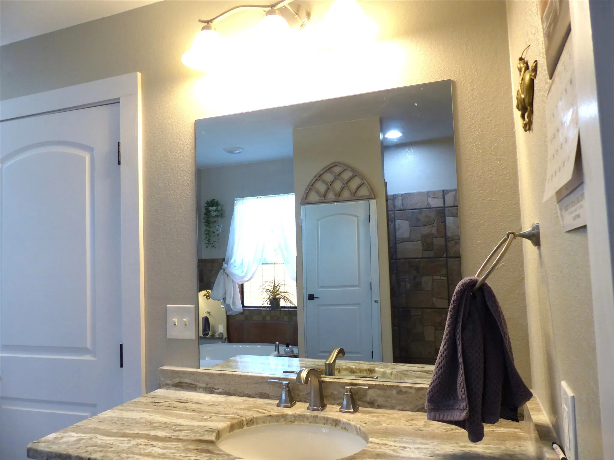Full bathroom featuring a textured wall, vanity, and a tub