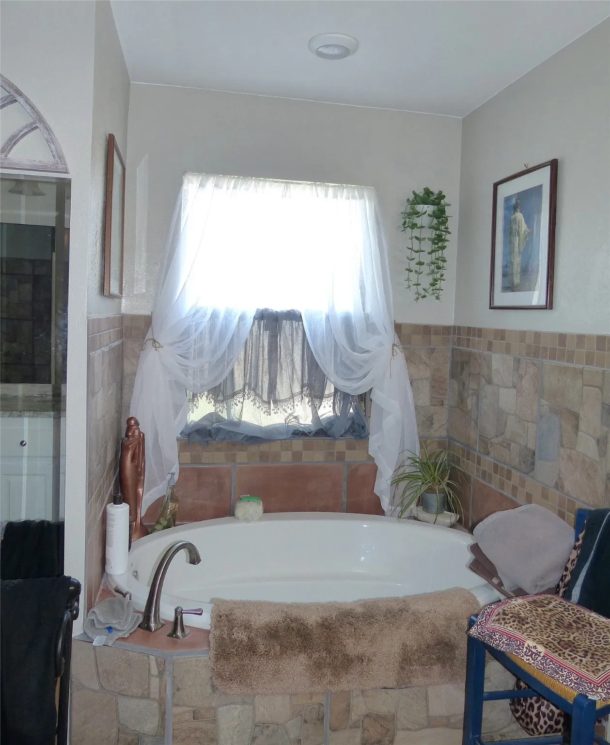 Bathroom with a garden tub, wainscoting, and tile walls