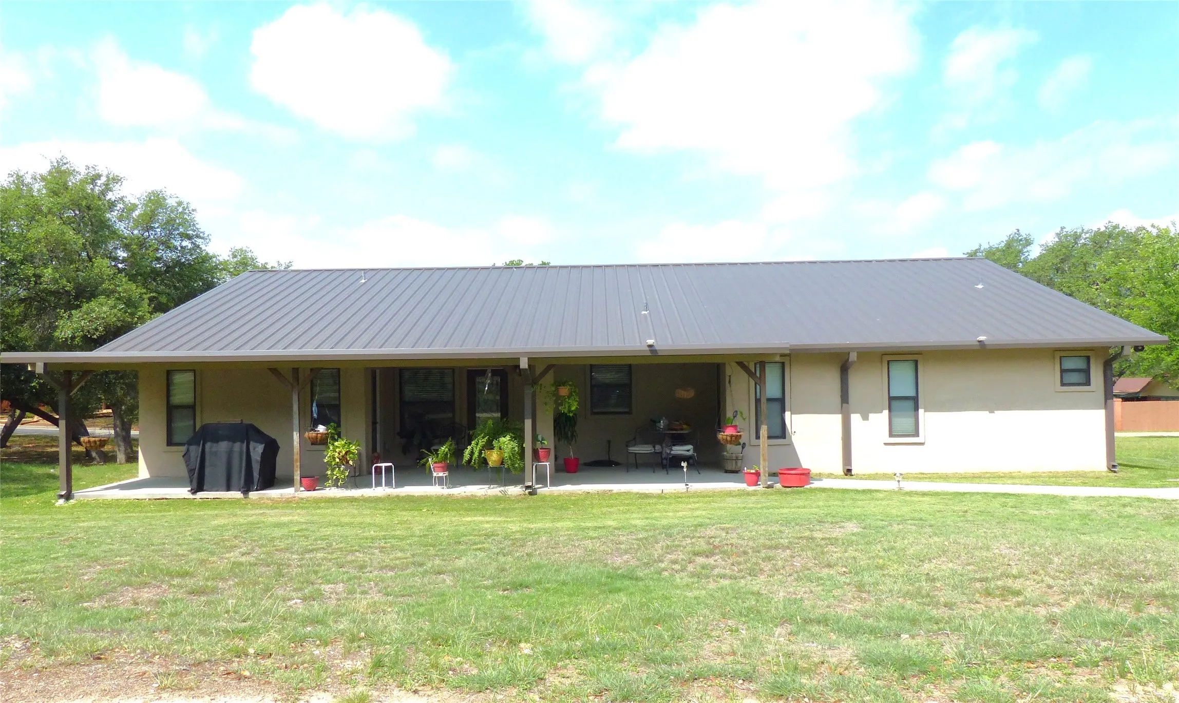 Back of property featuring a lawn, stucco siding, and a patio area