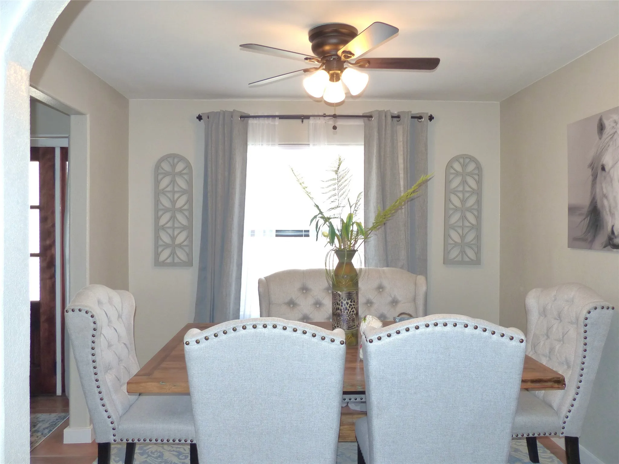 Dining room with arched walkways, a ceiling fan, and wood finished floors