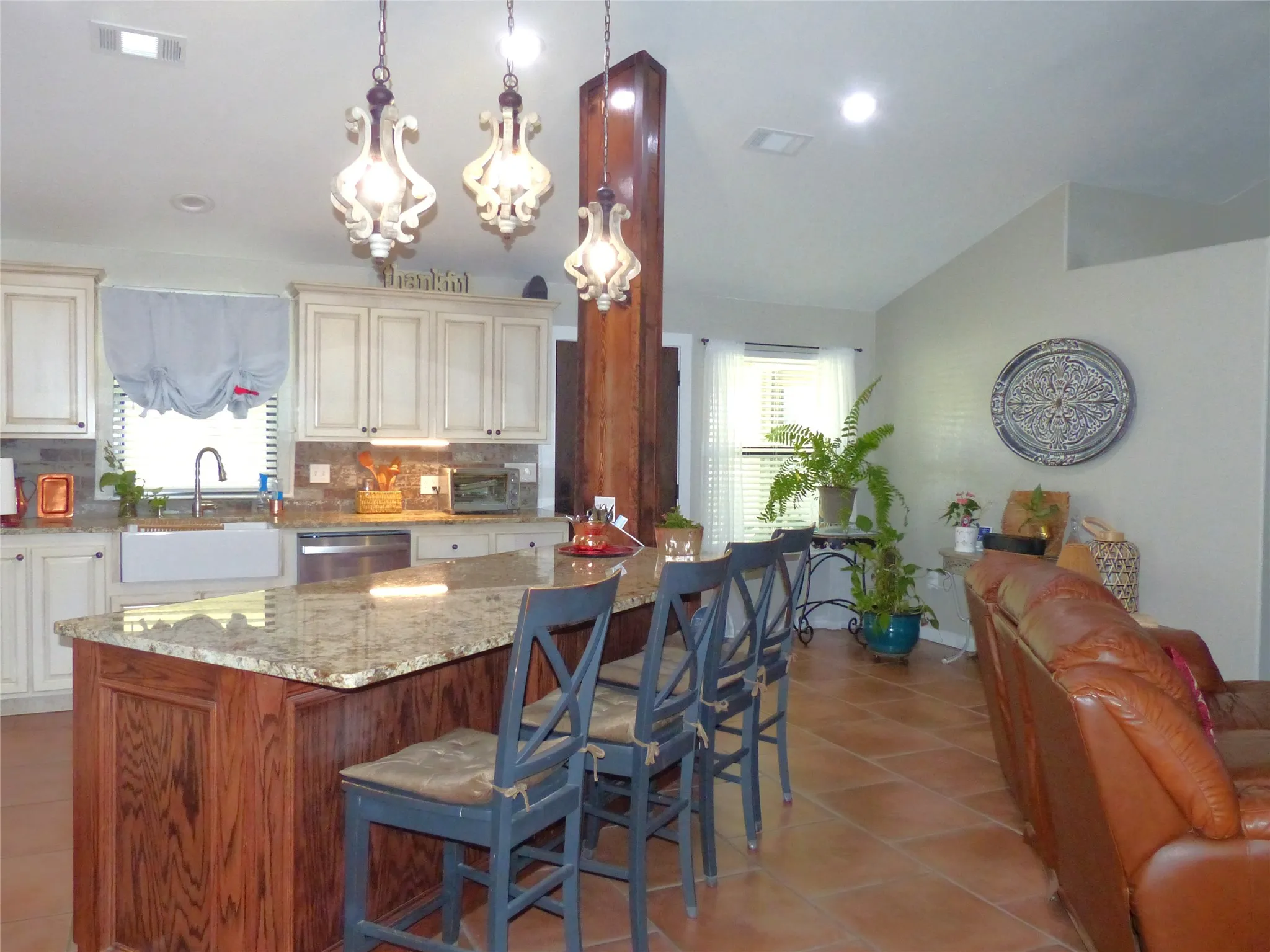 Kitchen featuring stainless steel dishwasher, light tile patterned floors, a healthy amount of sunlight, and cream cabinetry