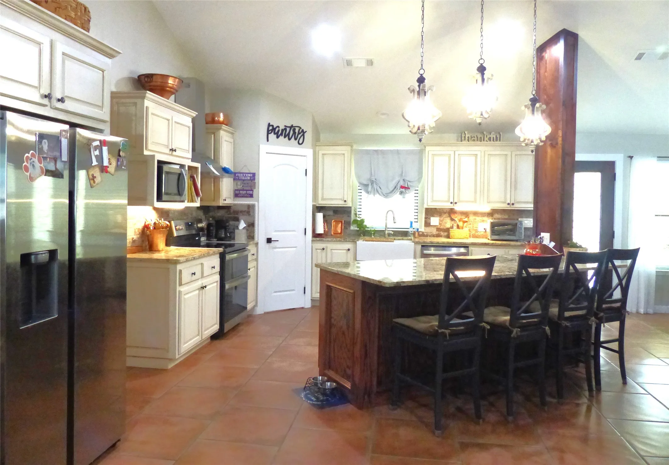 Kitchen with decorative backsplash, visible vents, appliances with stainless steel finishes, tile patterned flooring, and lofted ceiling