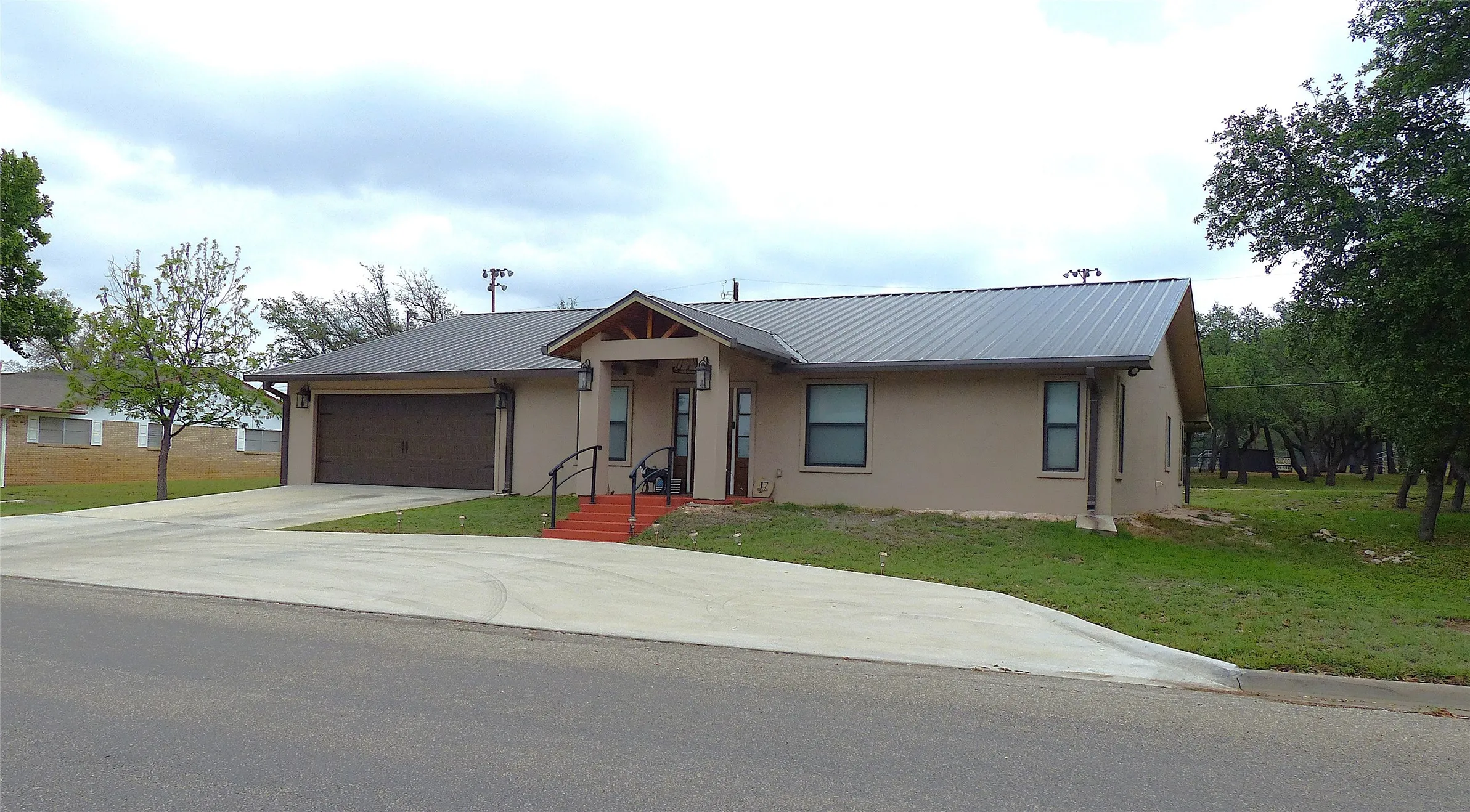 View of front of house with concrete driveway, a garage, metal roof, and stucco siding