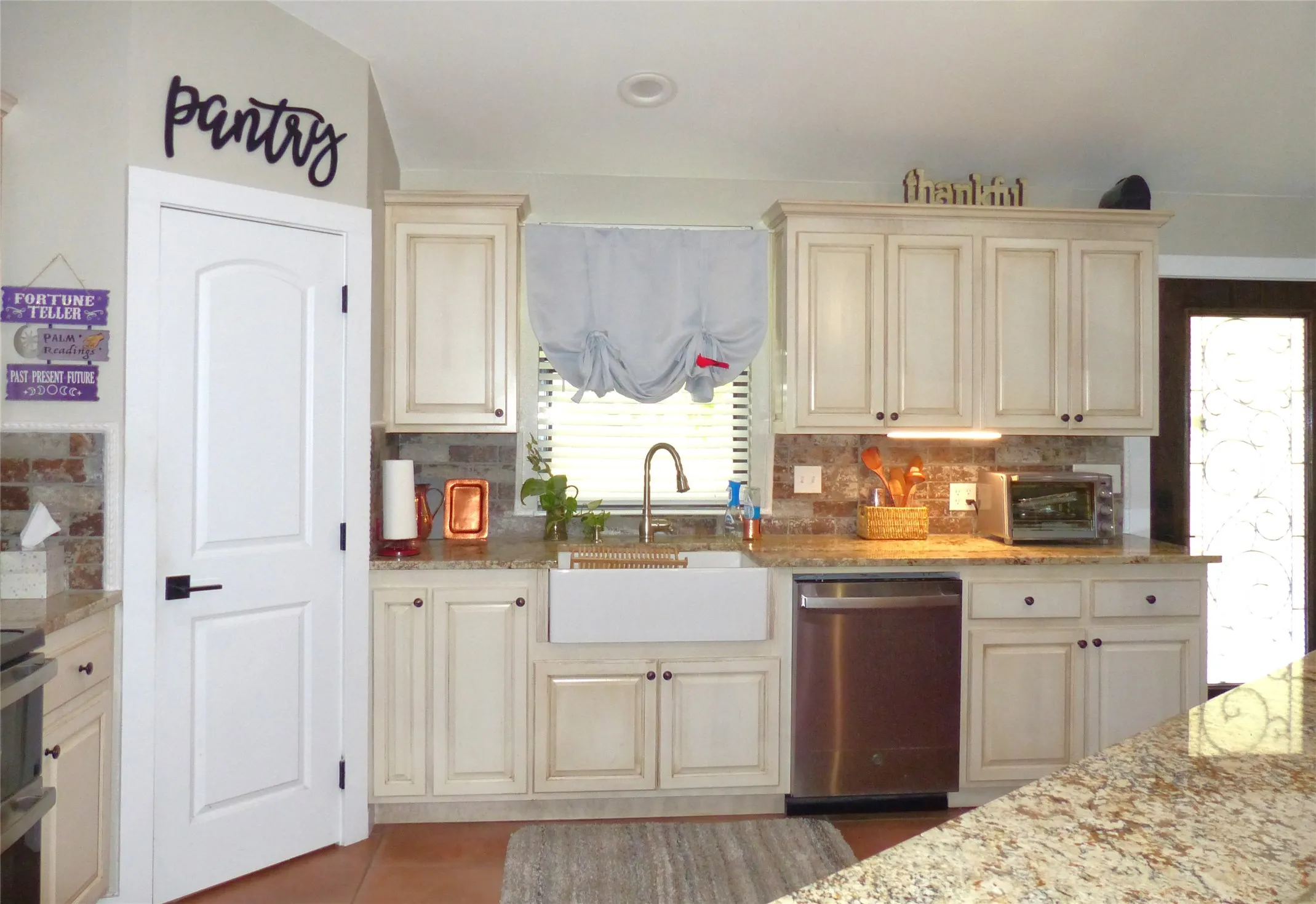 Kitchen with a sink, backsplash, dishwasher, and cream cabinets