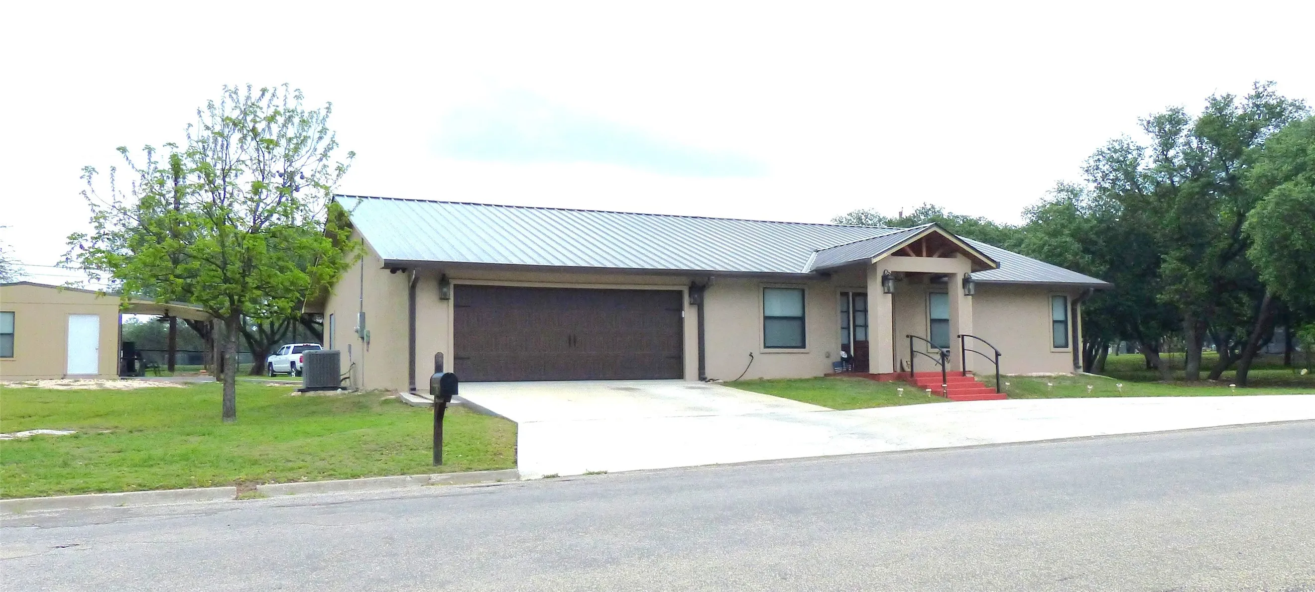 Ranch-style house with a garage, a front lawn, stucco siding, and concrete driveway