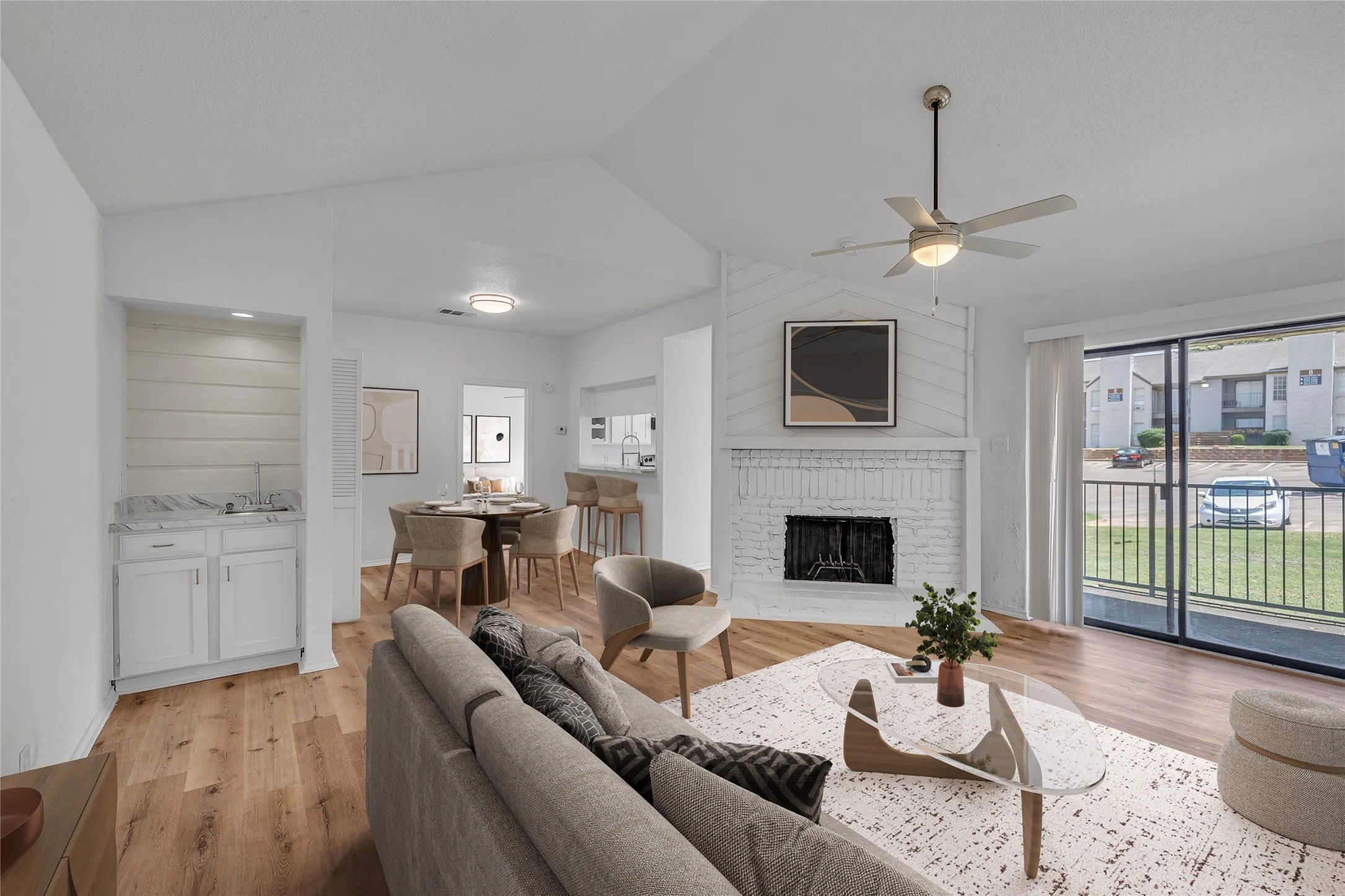 Living area with a brick fireplace, light wood-style floors, a ceiling fan, and lofted ceiling