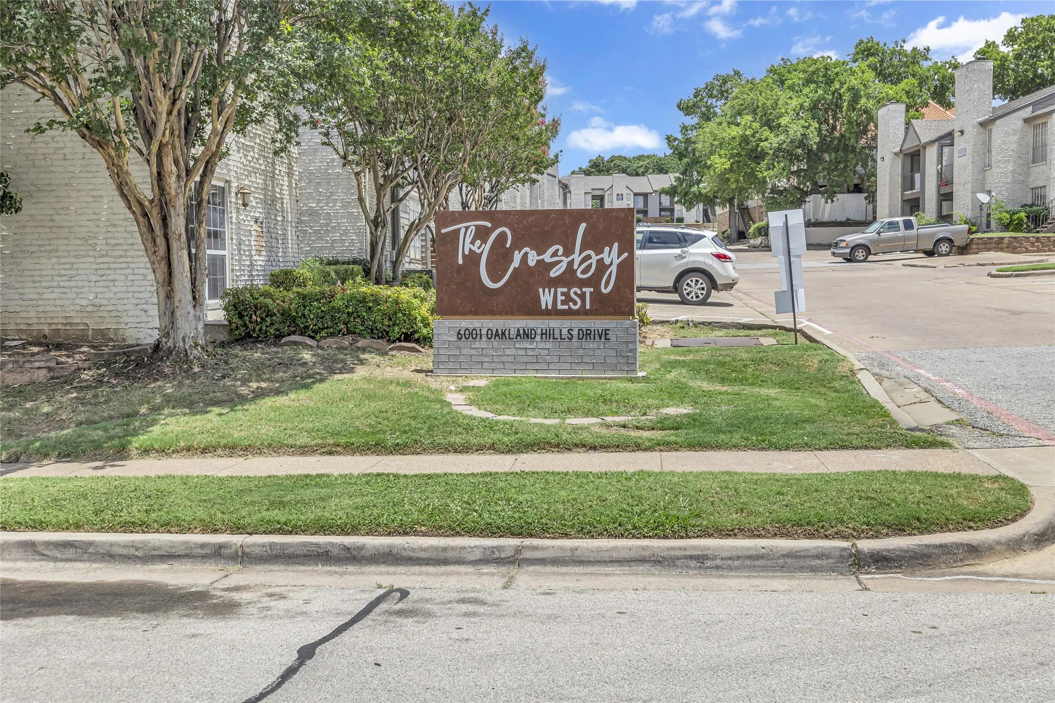 Community sign with uncovered parking and a residential view