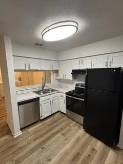 Kitchen featuring wood-finish flooring, white cabinetry, and light countertops