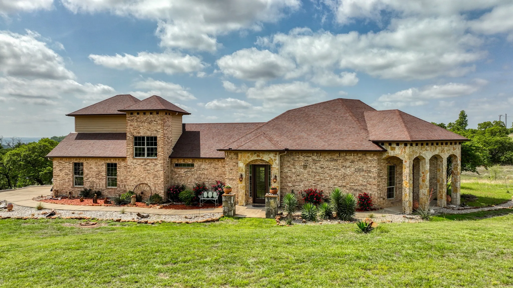 View of front facade with brick siding, roof with shingles, stone siding, and a front yard