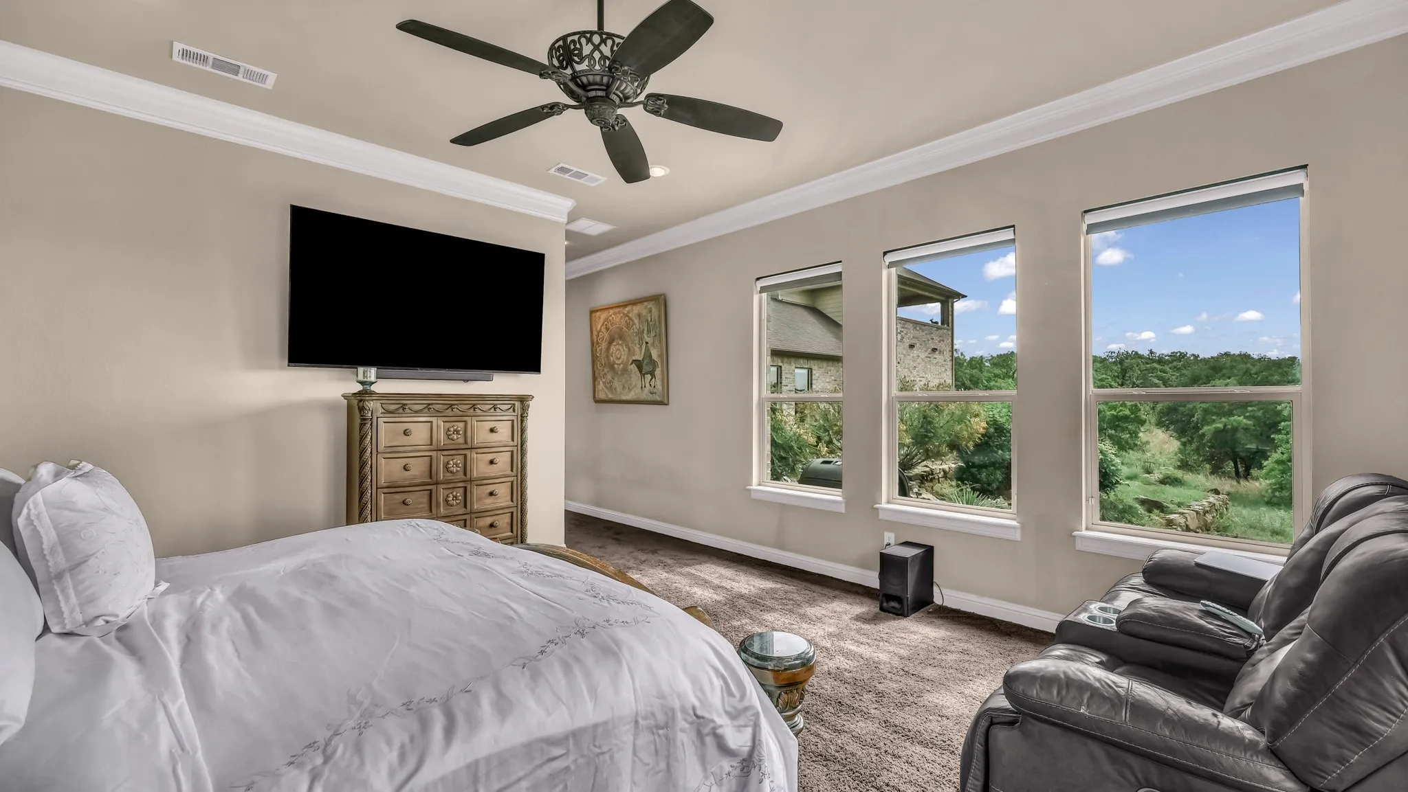 Carpeted bedroom featuring crown molding, baseboards, a ceiling fan, and visible vents