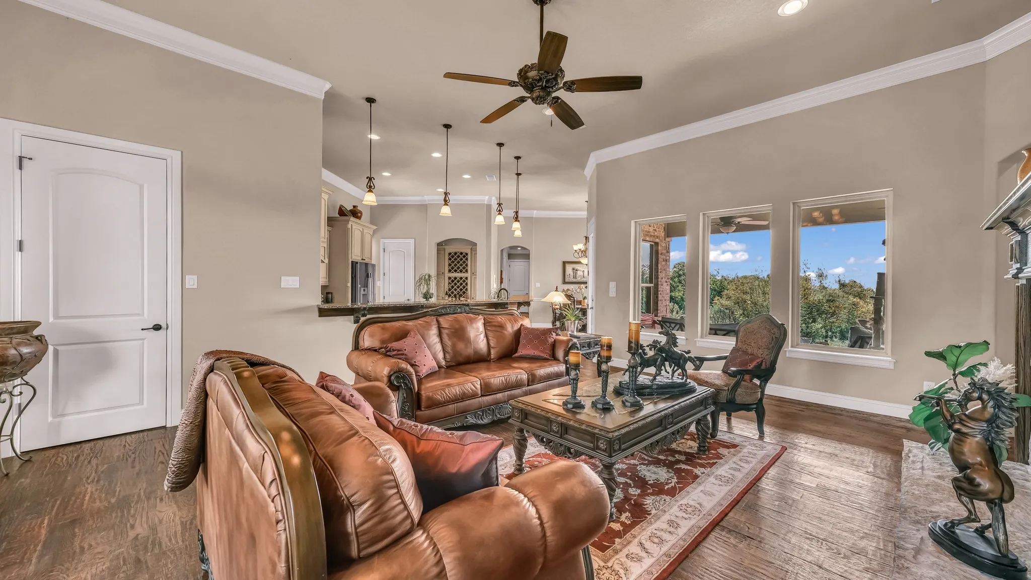 Living room featuring a ceiling fan, crown molding, wood finished floors, baseboards, and recessed lighting