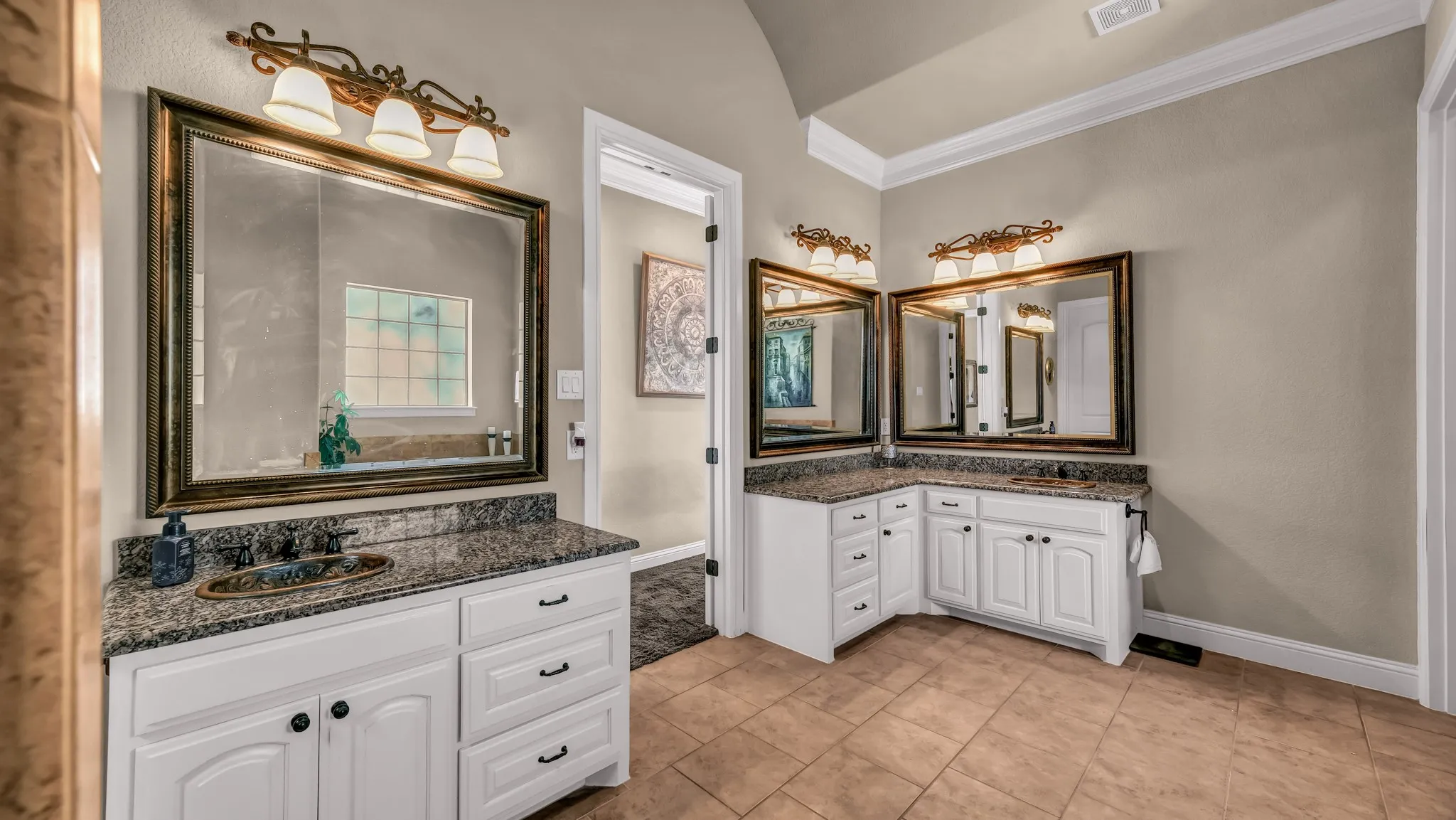 Bathroom with crown molding, visible vents, baseboards, two vanities, and a sink