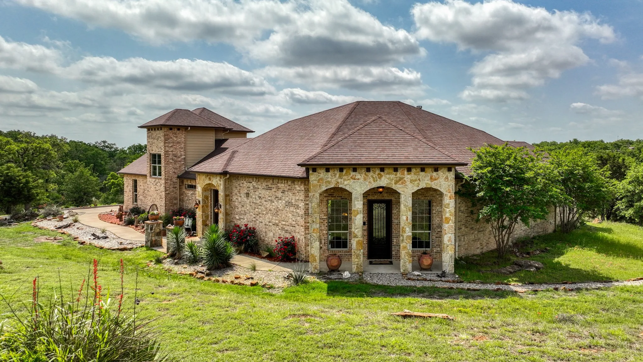 View of front of property featuring a shingled roof, stone siding, and a front lawn