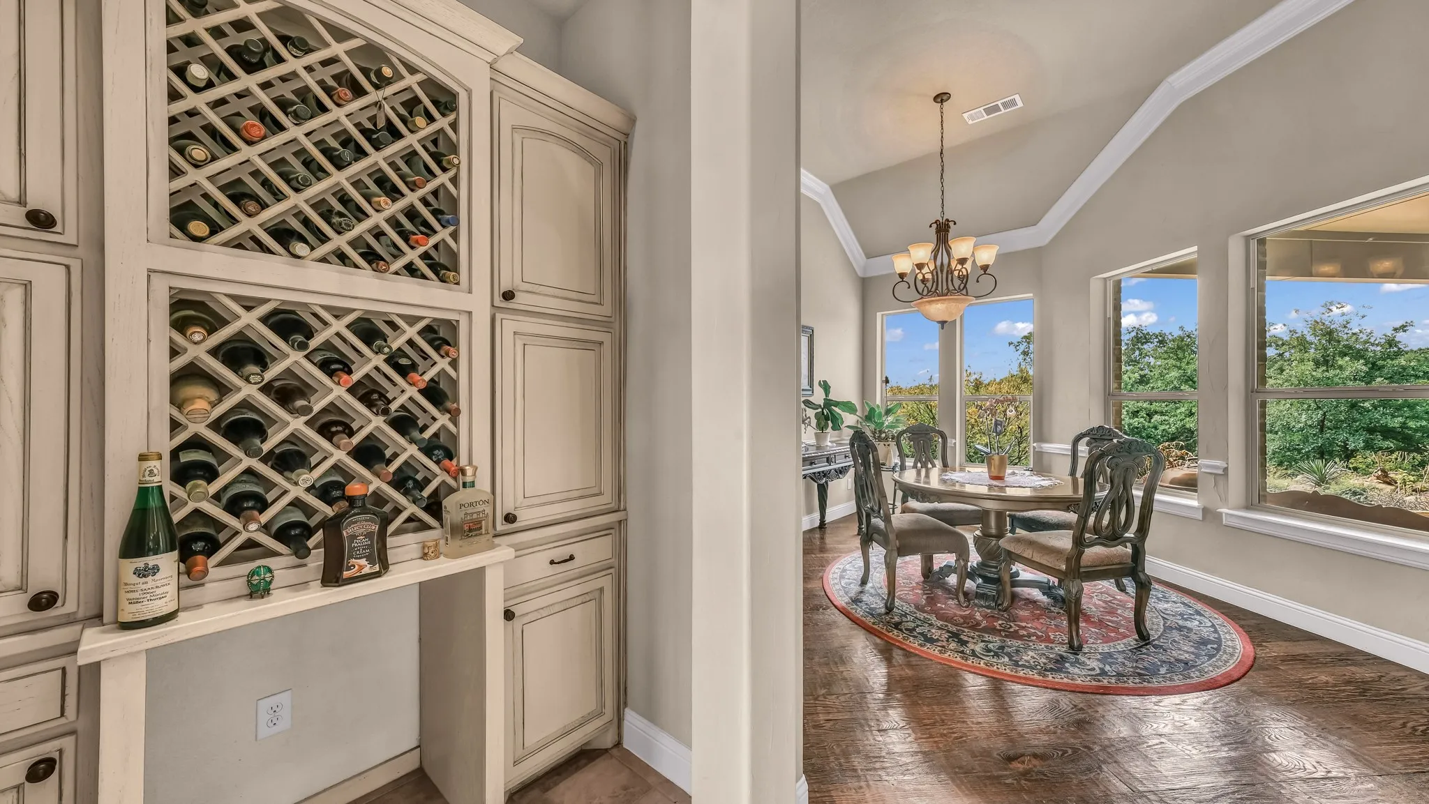 Wine cellar featuring a chandelier, visible vents, crown molding, baseboards, and lofted ceiling