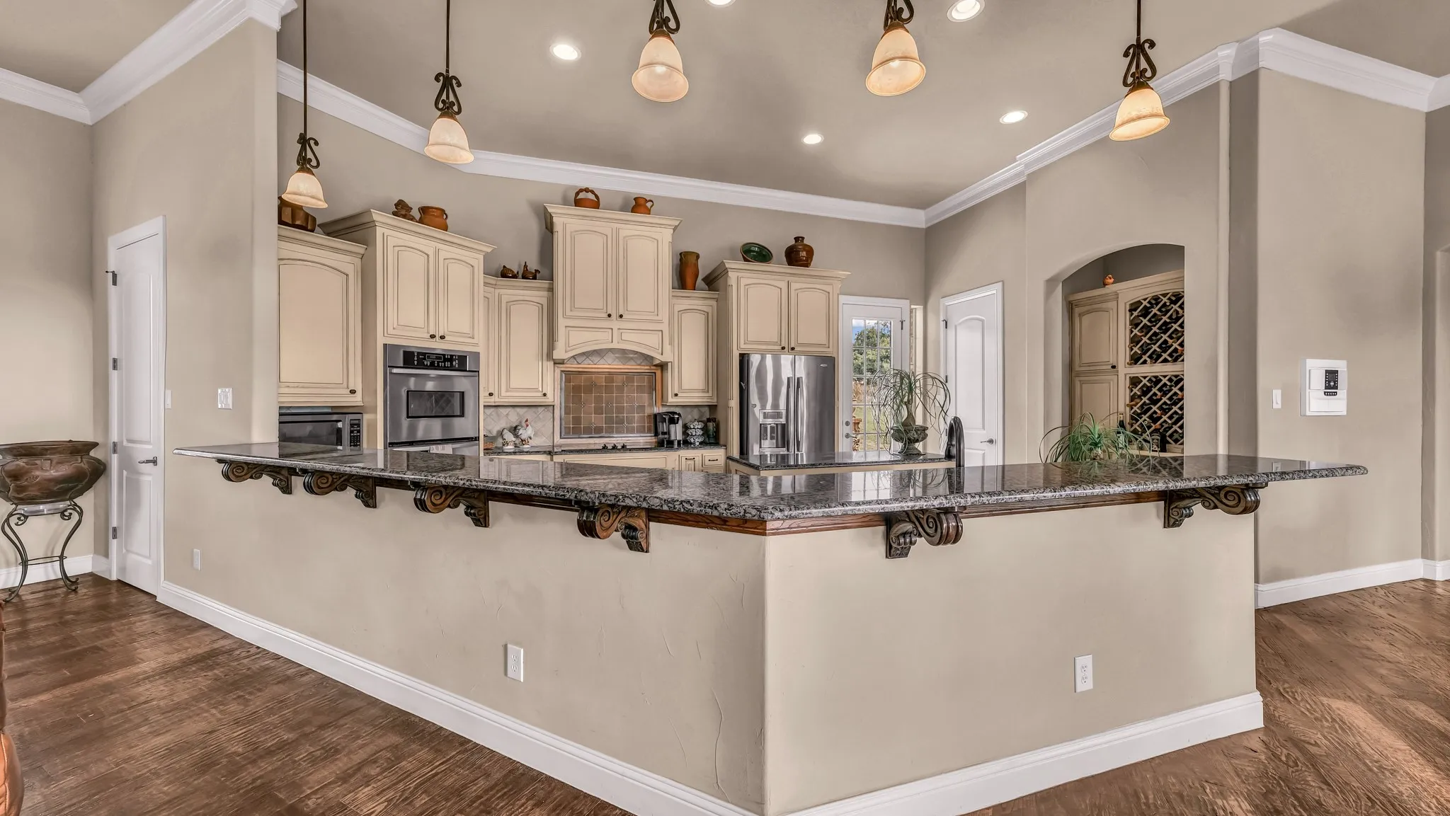 Kitchen with baseboards, a breakfast bar area, cream cabinets, backsplash, and stainless steel appliances