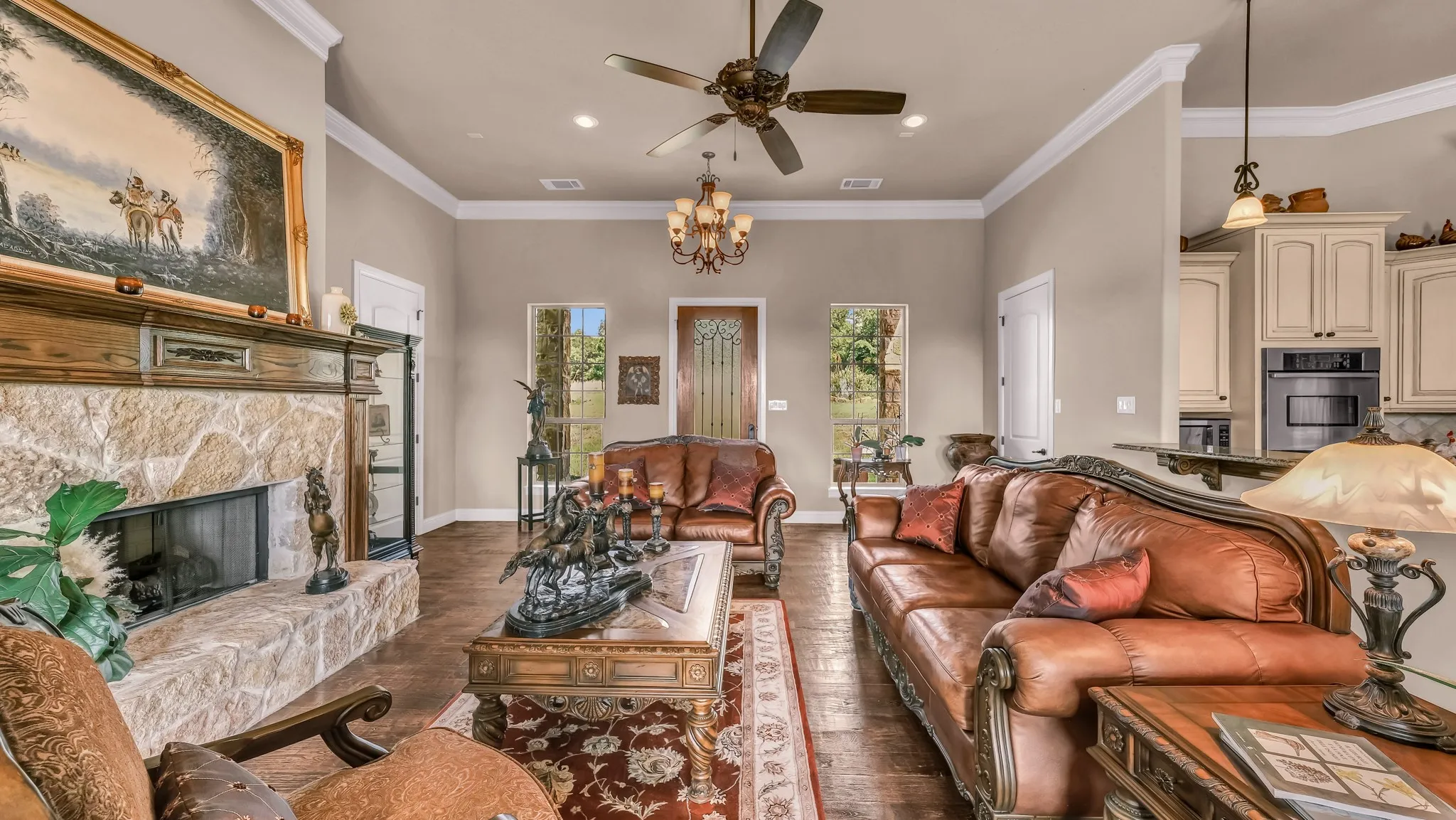 Living area featuring visible vents, dark wood-style floors, ornamental molding, and ceiling fan with notable chandelier