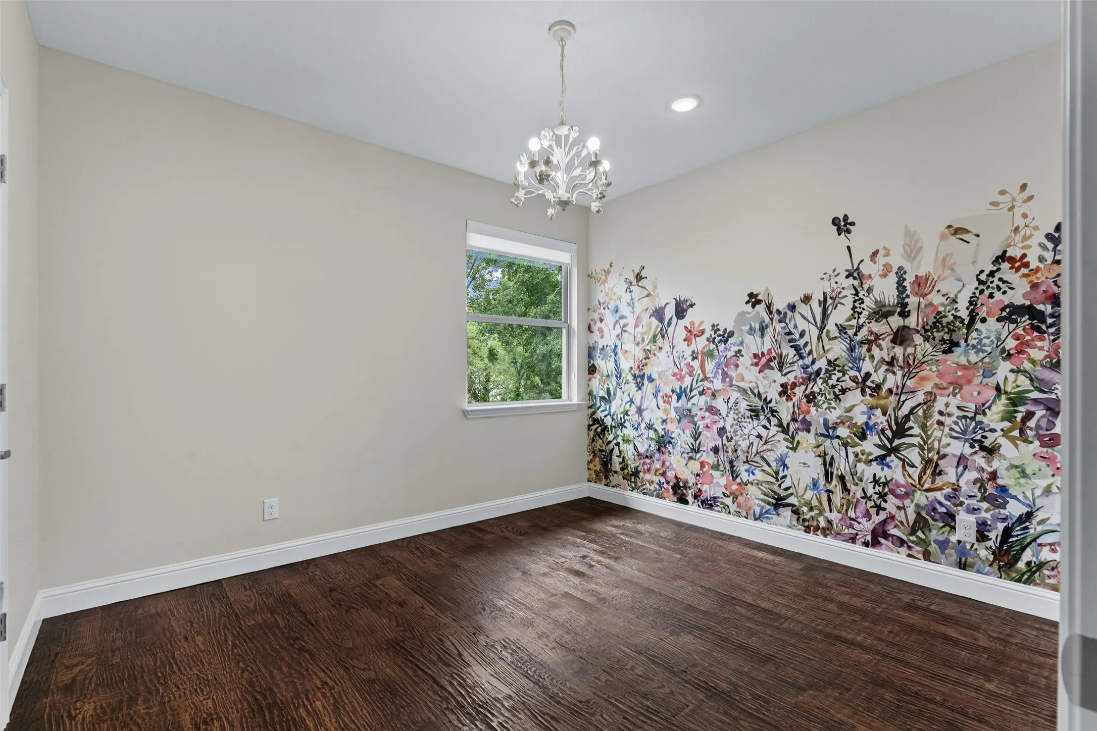 The second bedroom features chandelier lighting and a floral accent wall, complete with a spacious walk-in closet.