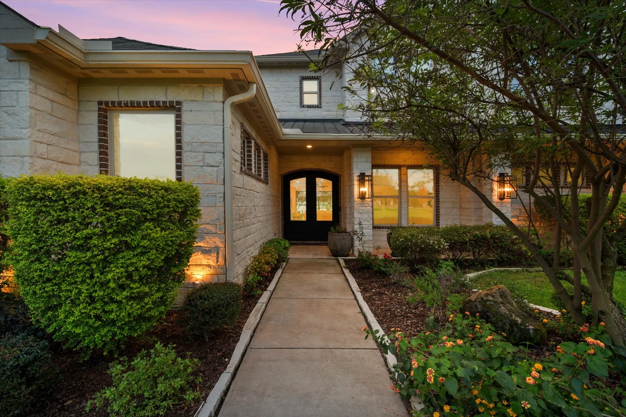 Charming stonework and lush landscaping create an inviting front approach.