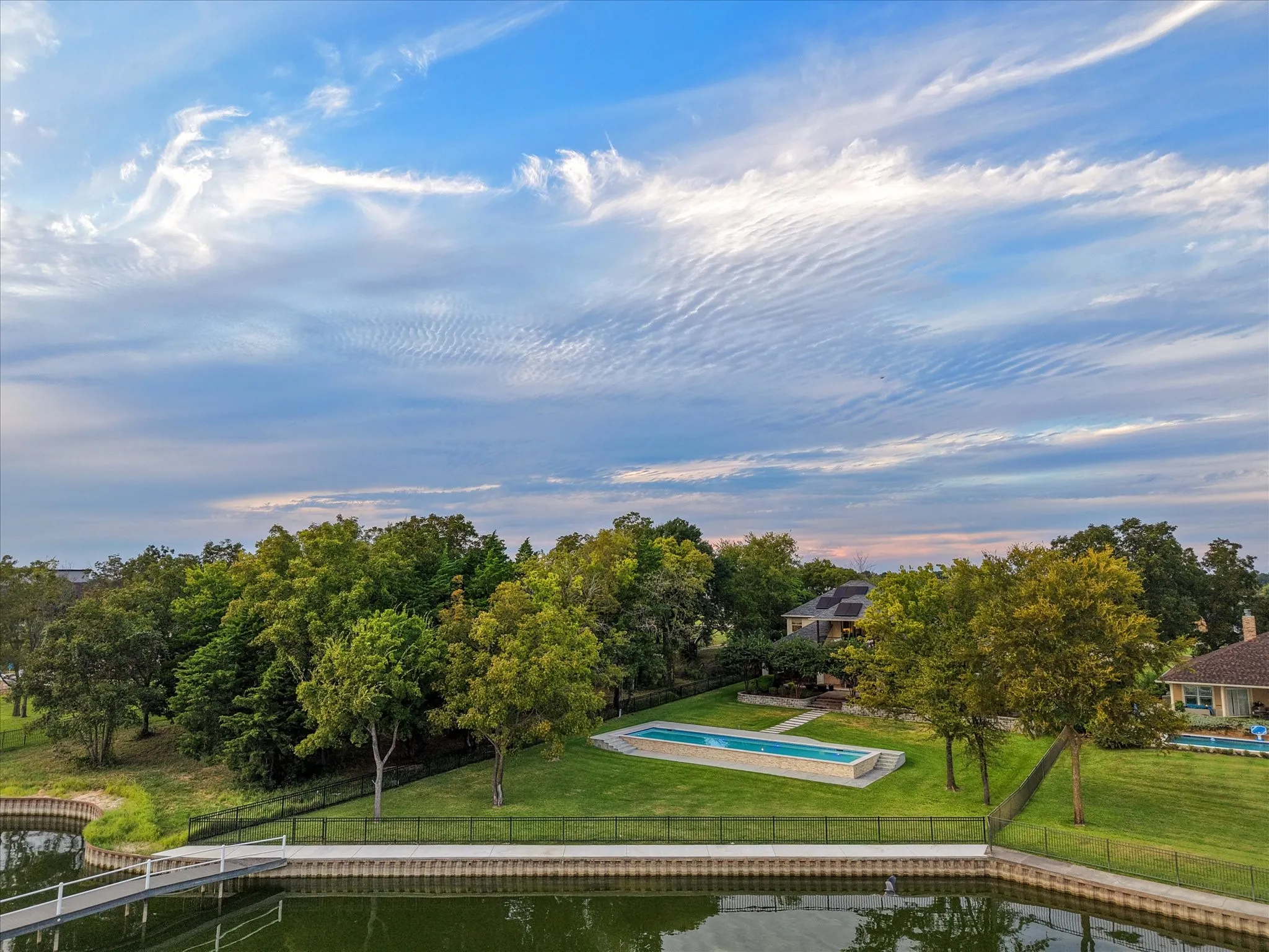 The seawall frames the backyard, pool, and residence, emphasizing the property’s scale and setting.