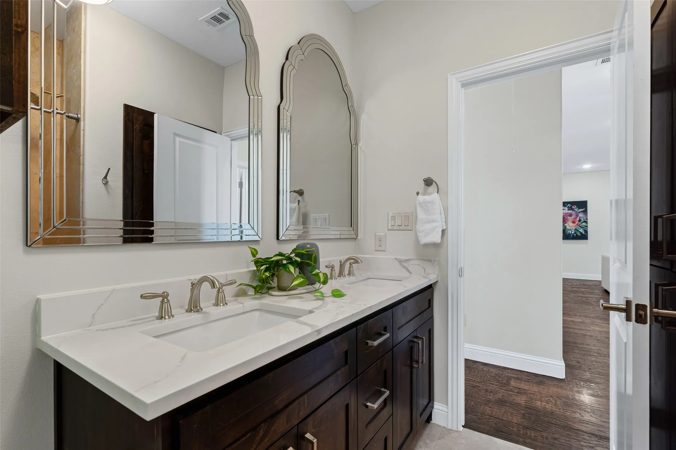 The bathroom features dual vanities with quartz counters, rich cabinetry (including linen storage), and designer mirrors.