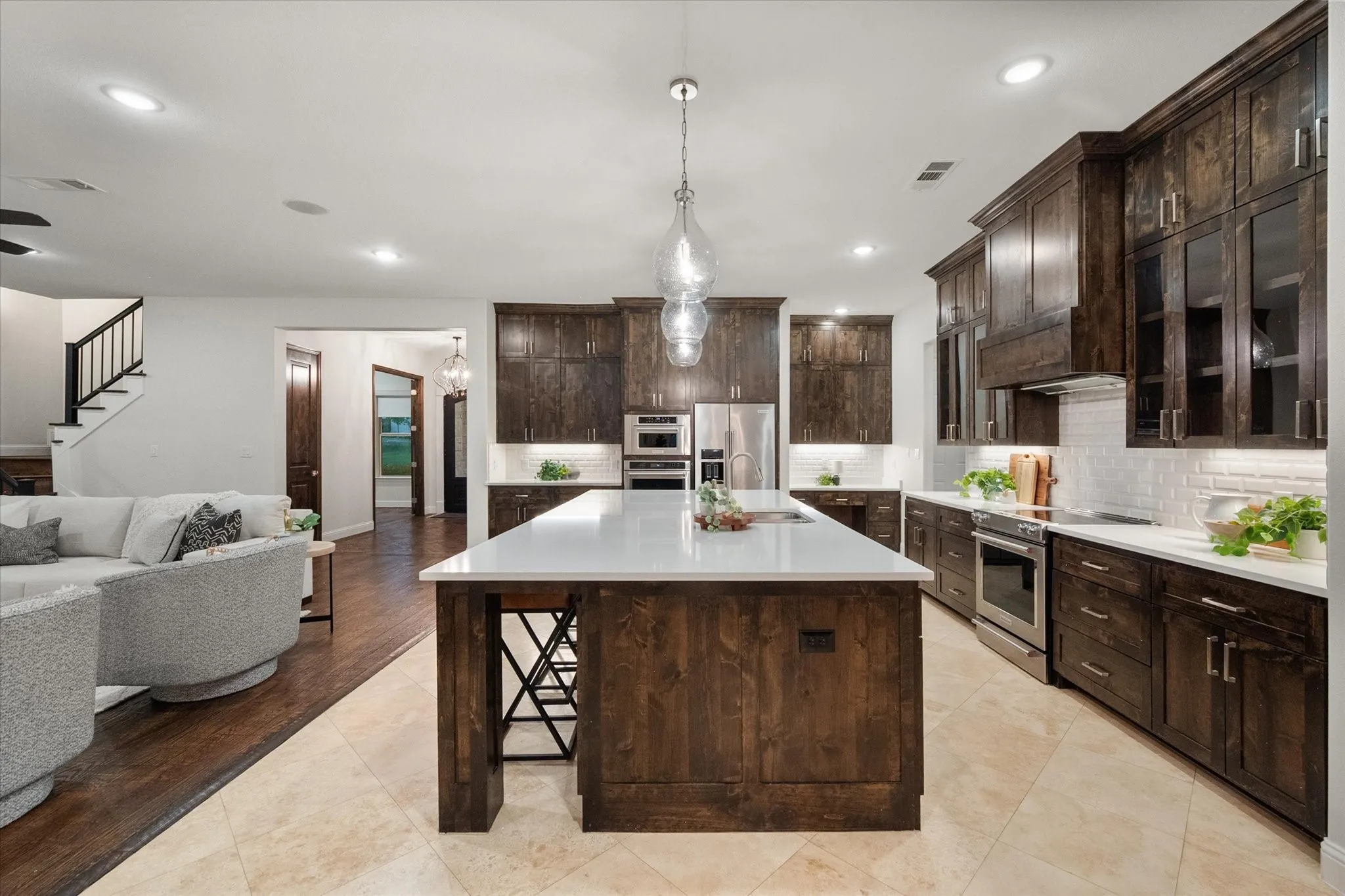 The kitchen showcases an oversized island, quartz counters, and rich custom cabinetry.