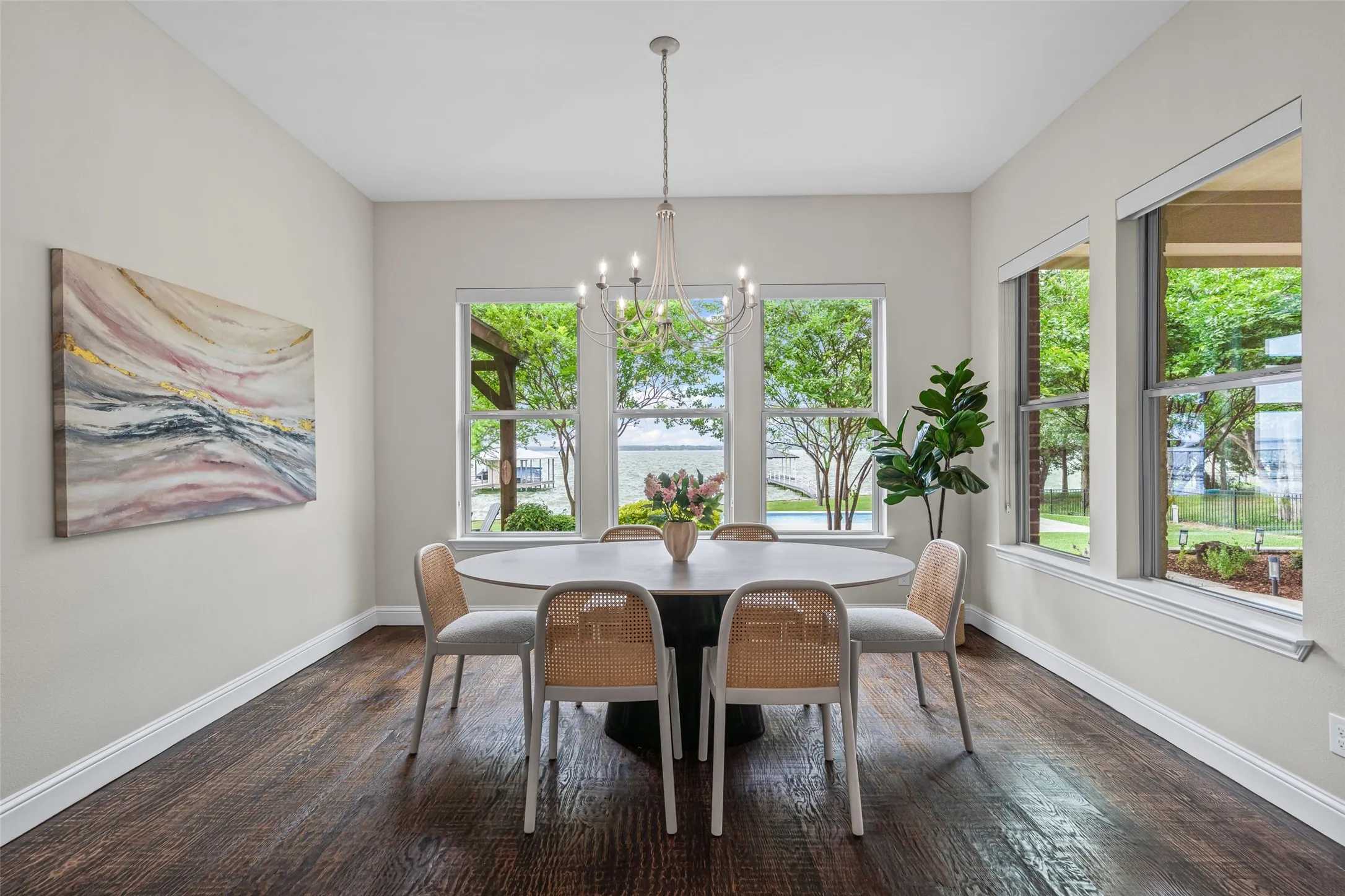 The dining room, surrounded by windows overlooking the water, offers a serene backdrop for meals.