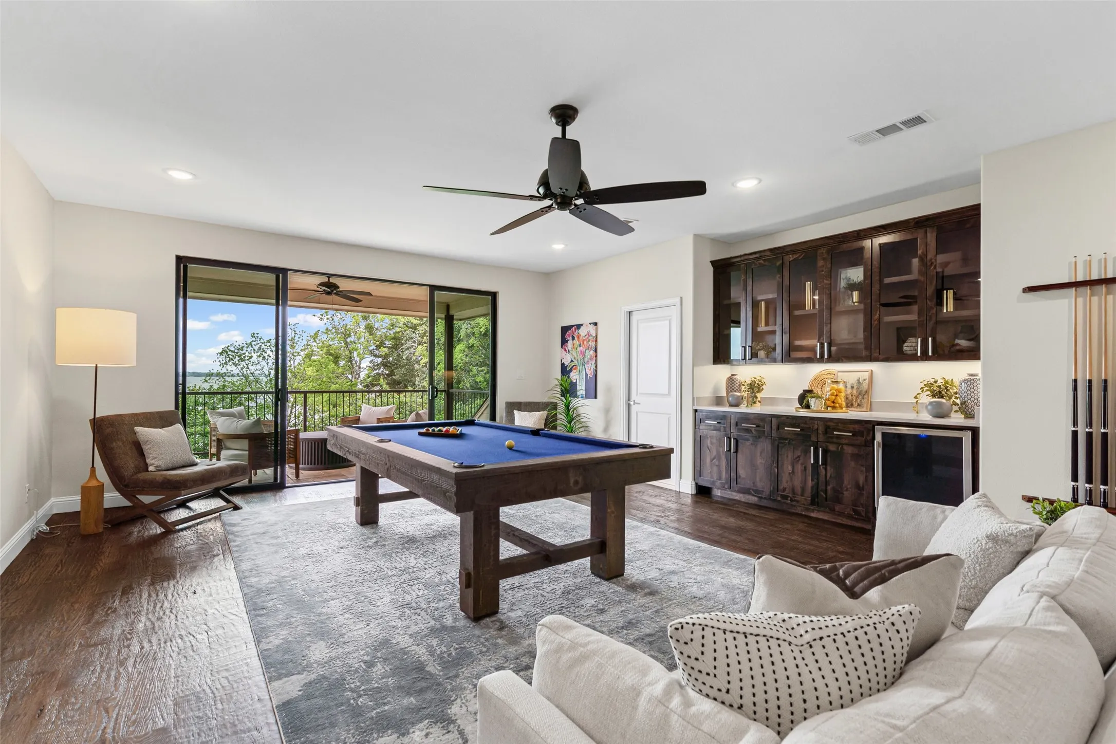 The upstairs game room opens to the balcony through wide glass doors and features custom built-in cabinetry and a wine fridge, creating the ideal space for entertaining.