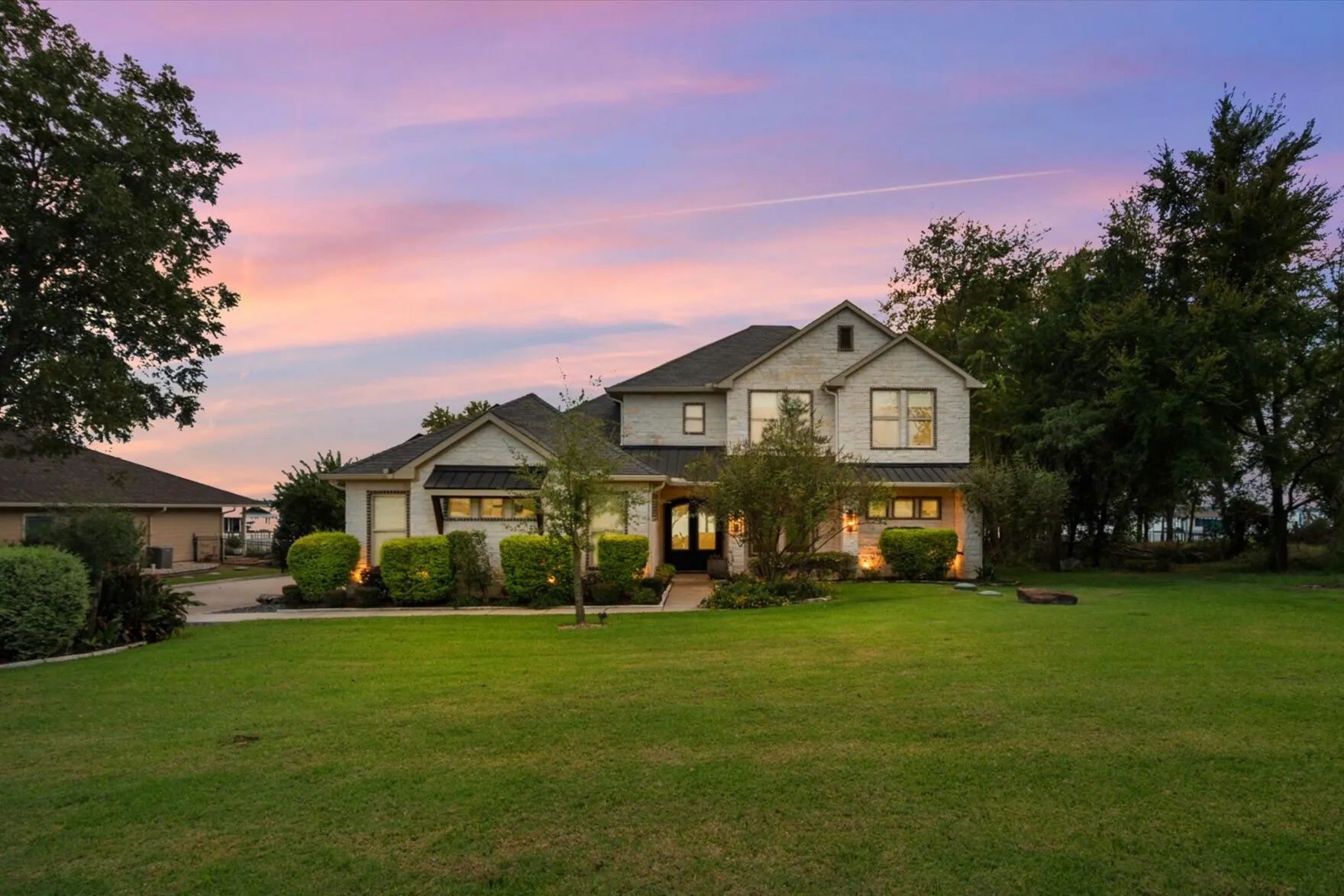 The stone exterior glows against manicured landscaping and a wide Texas sky.