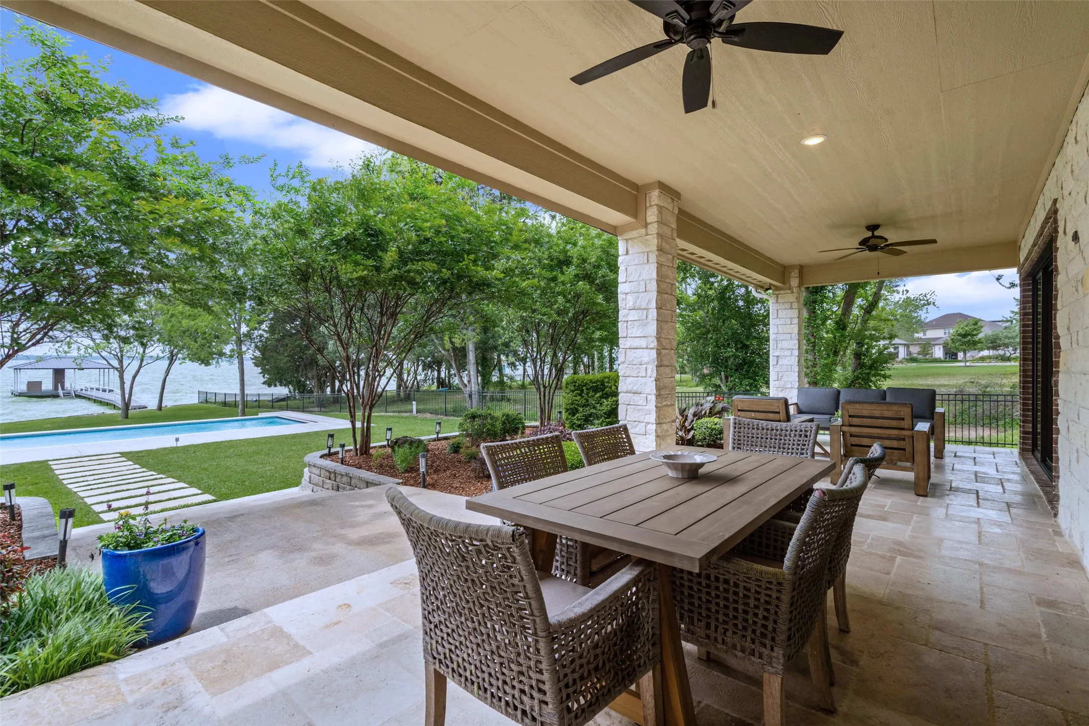 From another angle, the covered patio showcases shaded dining with views of the water and lush landscaping.