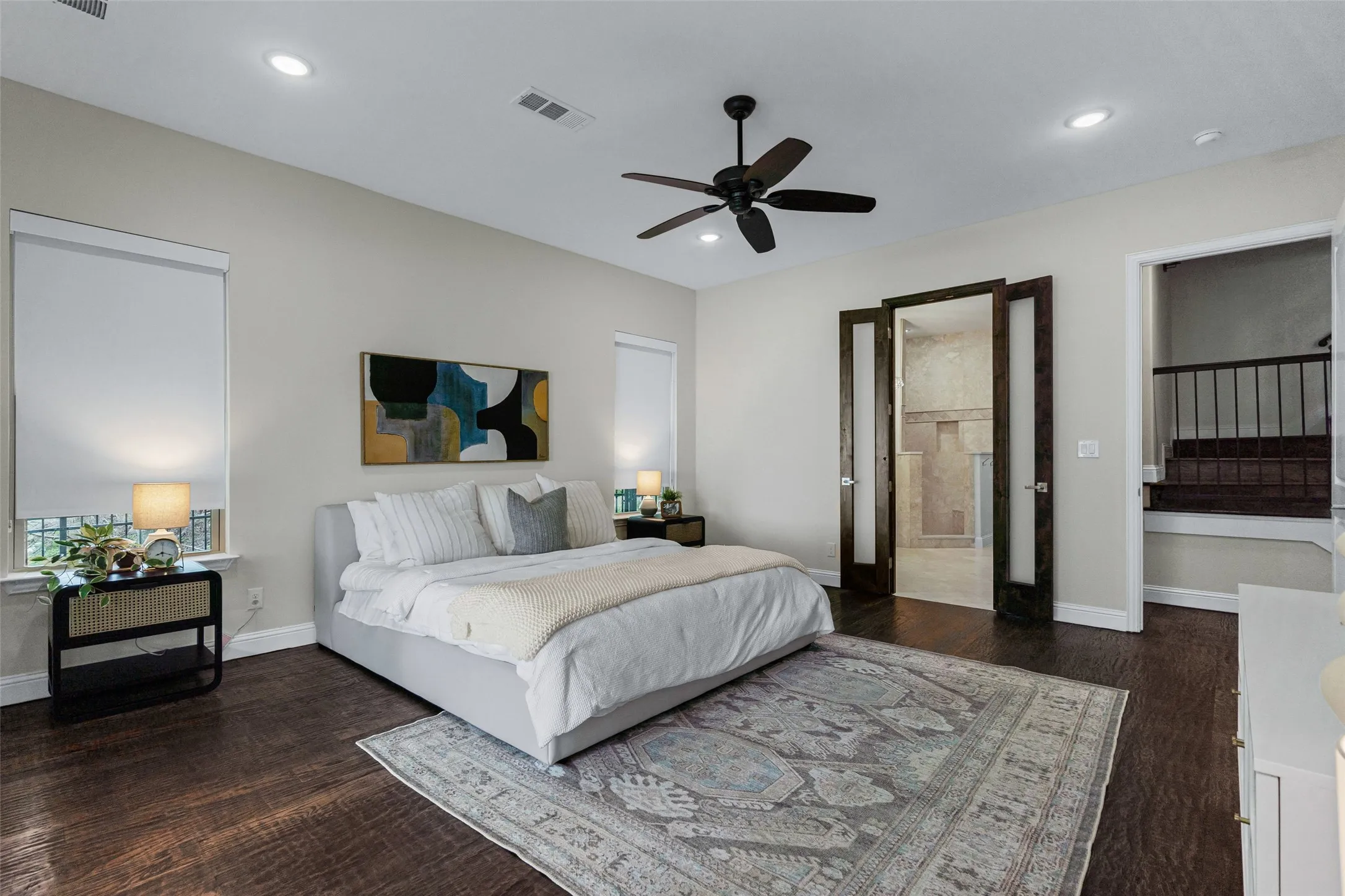 The primary bedroom offers a spacious retreat with wood floors, elegant French doors to the en suite, and serene natural light.
