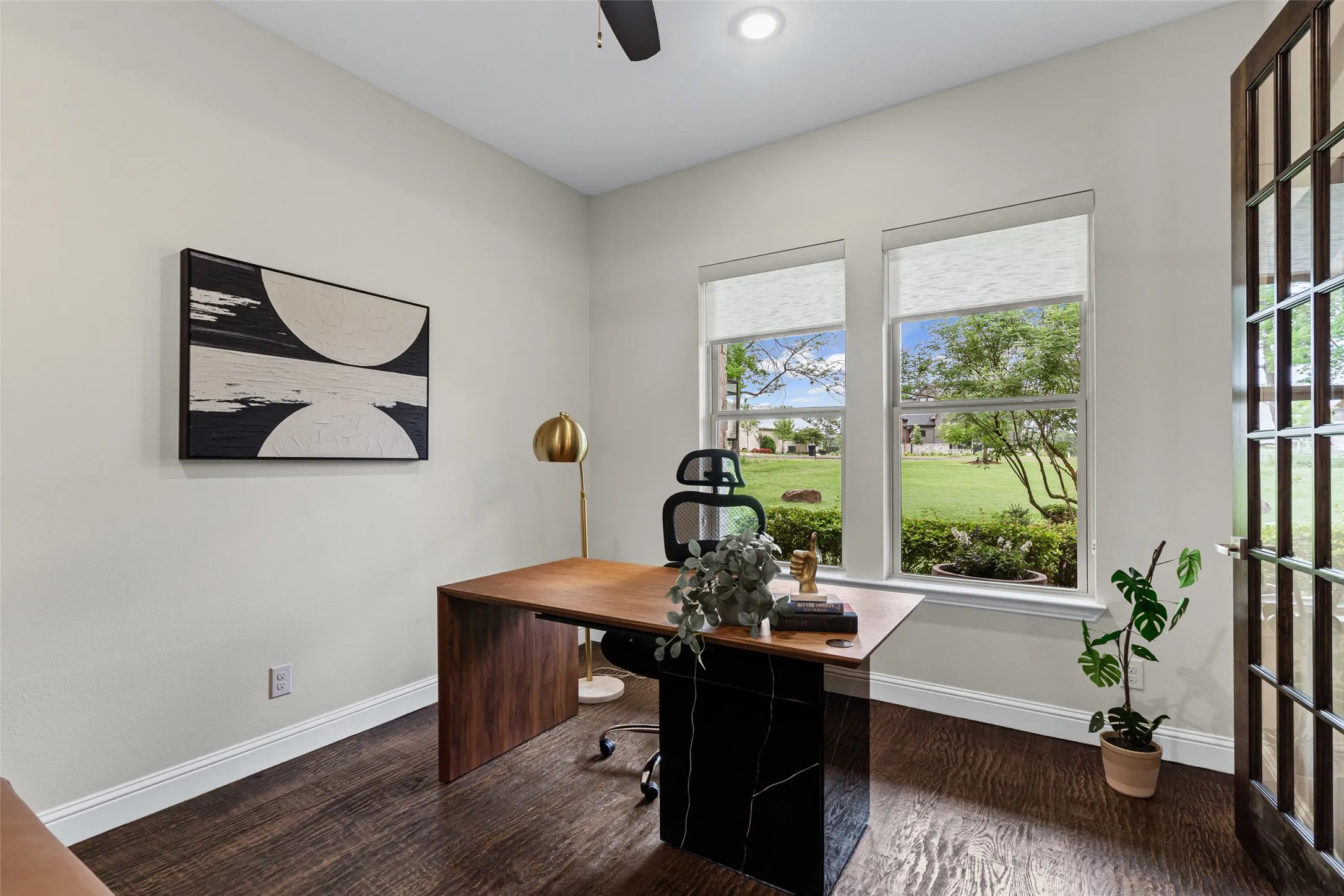 A private office with French doors and large windows overlooking the front lawn provides a bright, versatile workspace.