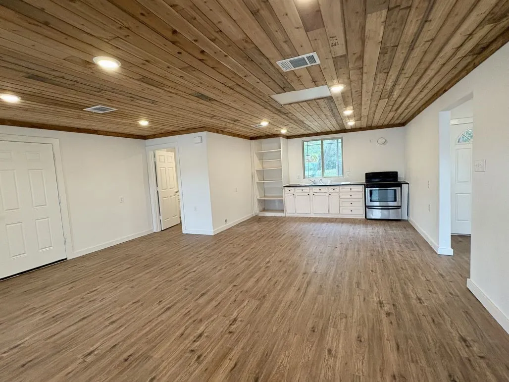 Unfurnished living room featuring wood ceiling, baseboards, visible vents, and wood finished floors