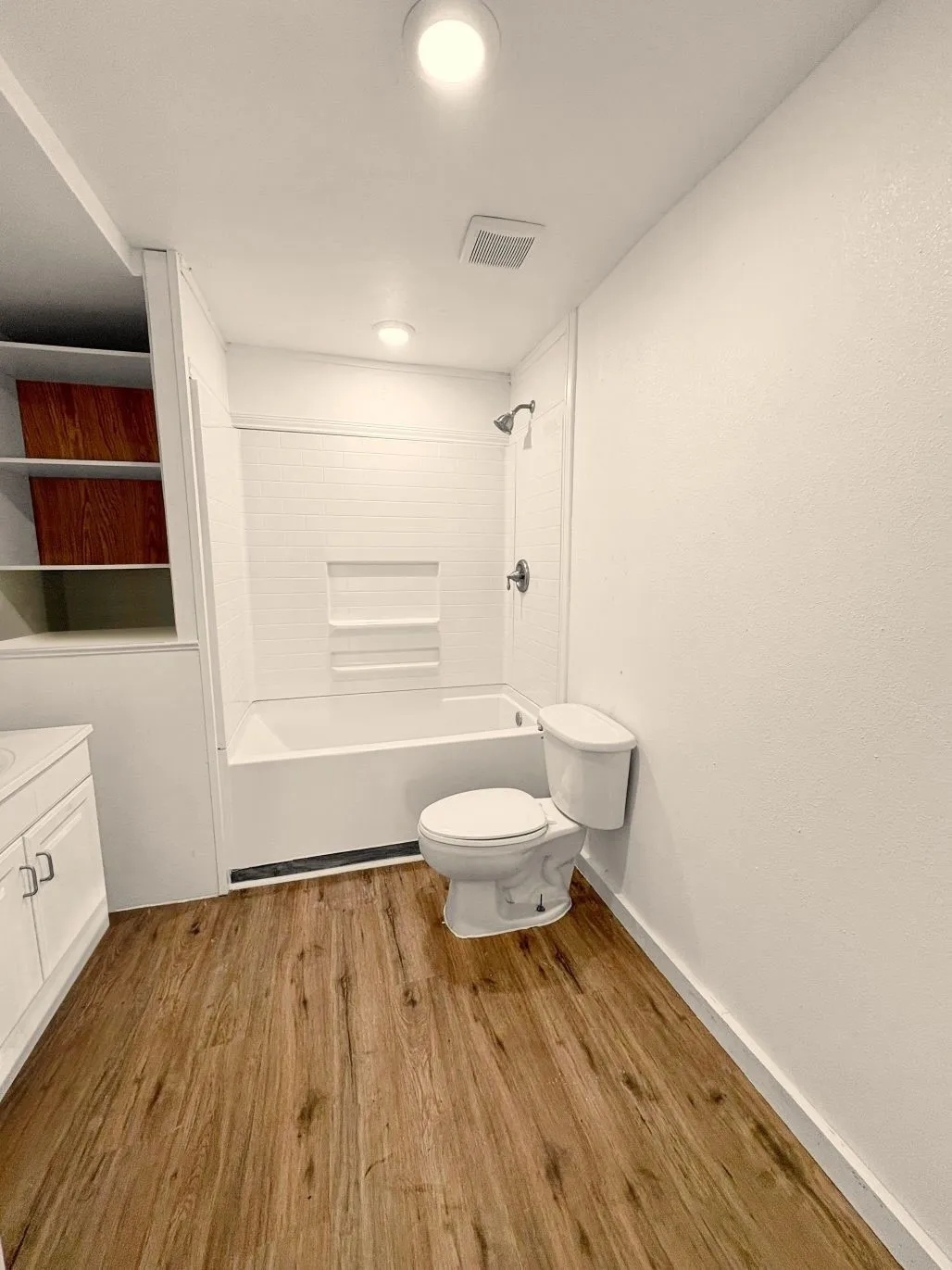 Full bath featuring toilet, wood finished floors,  shower combination, visible vents, and vanity