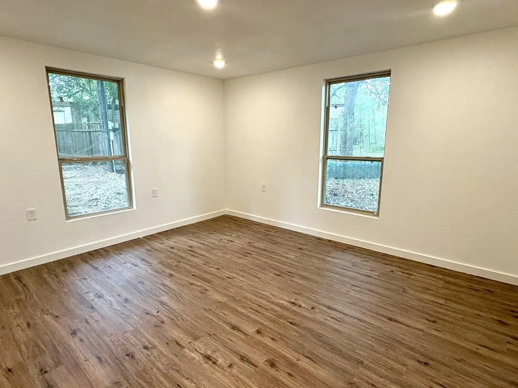 Unfurnished room featuring dark wood-type flooring, baseboards, a healthy amount of sunlight, and recessed lighting