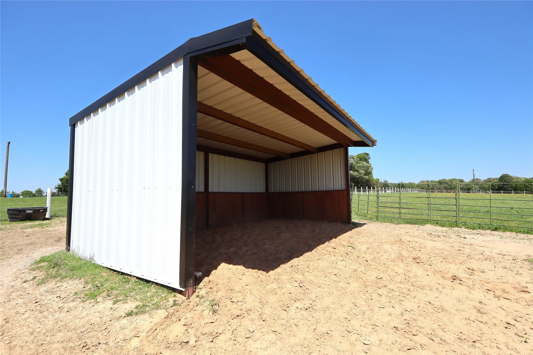 View of pole building featuring a detached carport, a rural view, and fence