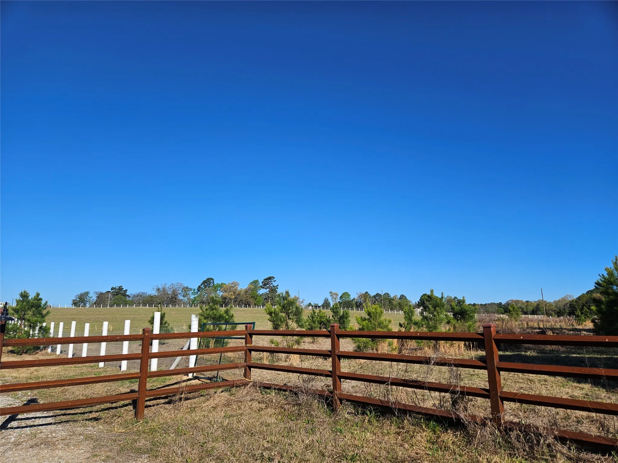 View of yard with fence and a rural view