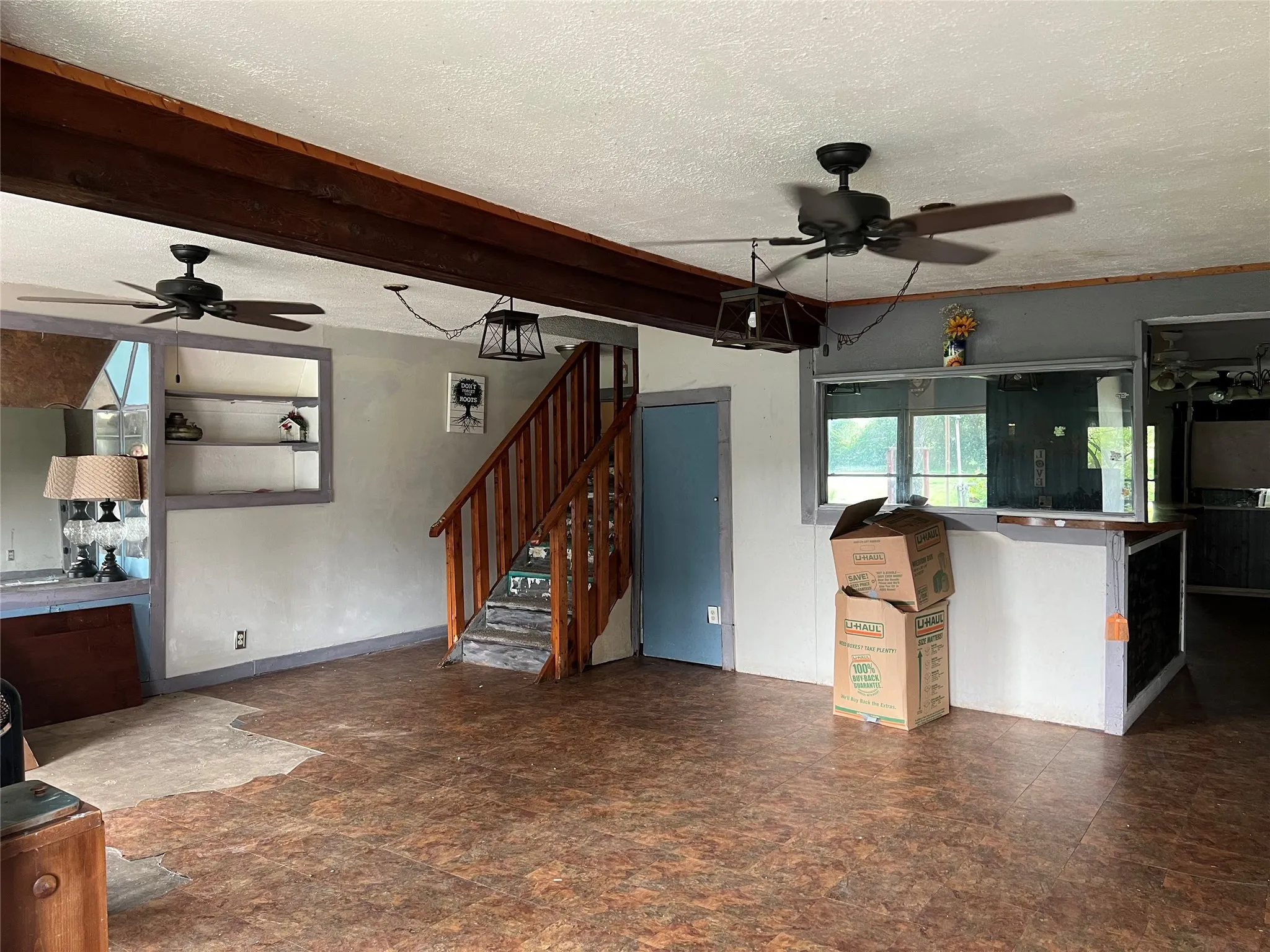 Unfurnished living room featuring a ceiling fan, a textured ceiling, and stairs