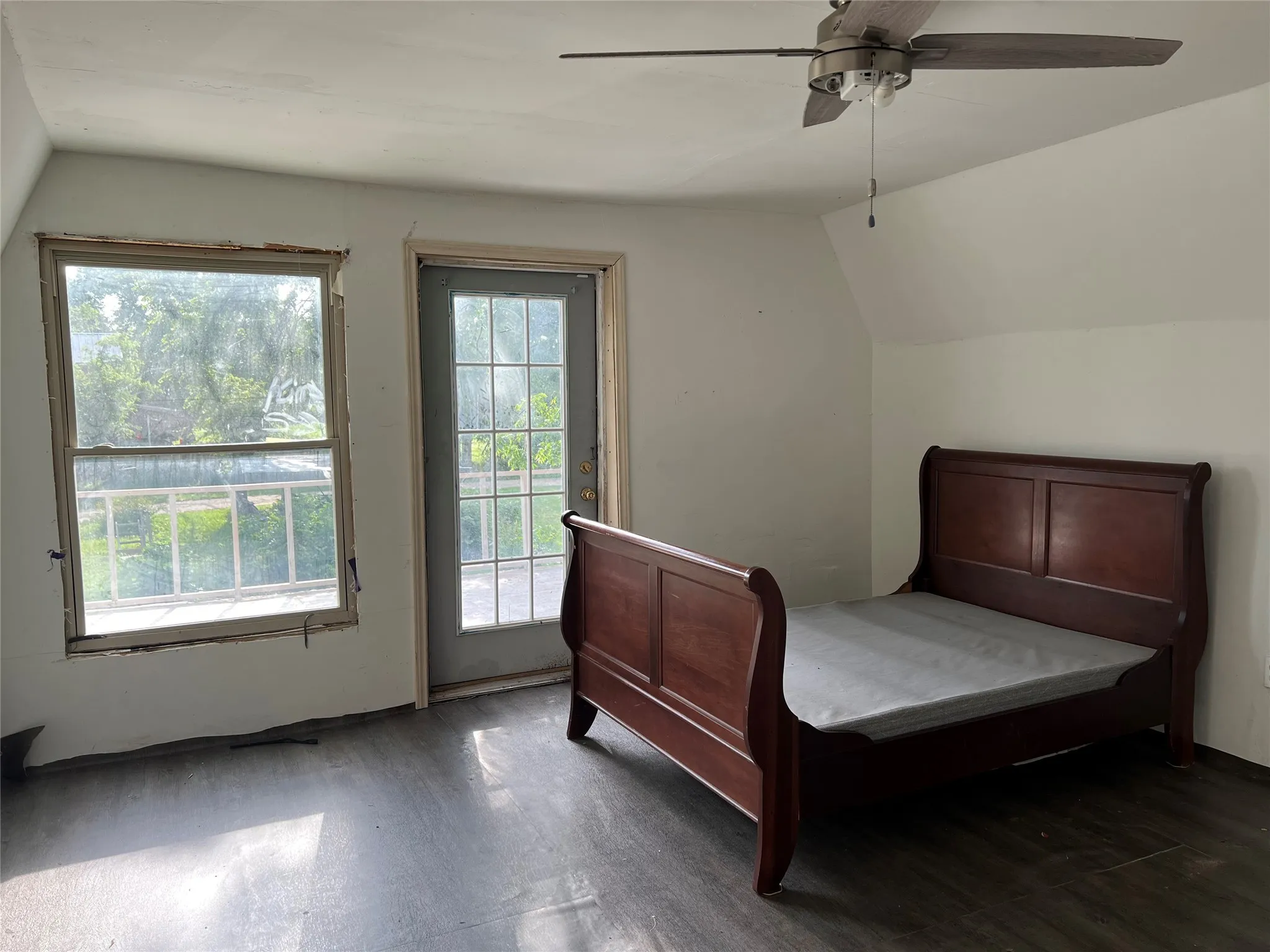 Bedroom featuring lofted ceiling, access to exterior, wood finished floors, and ceiling fan