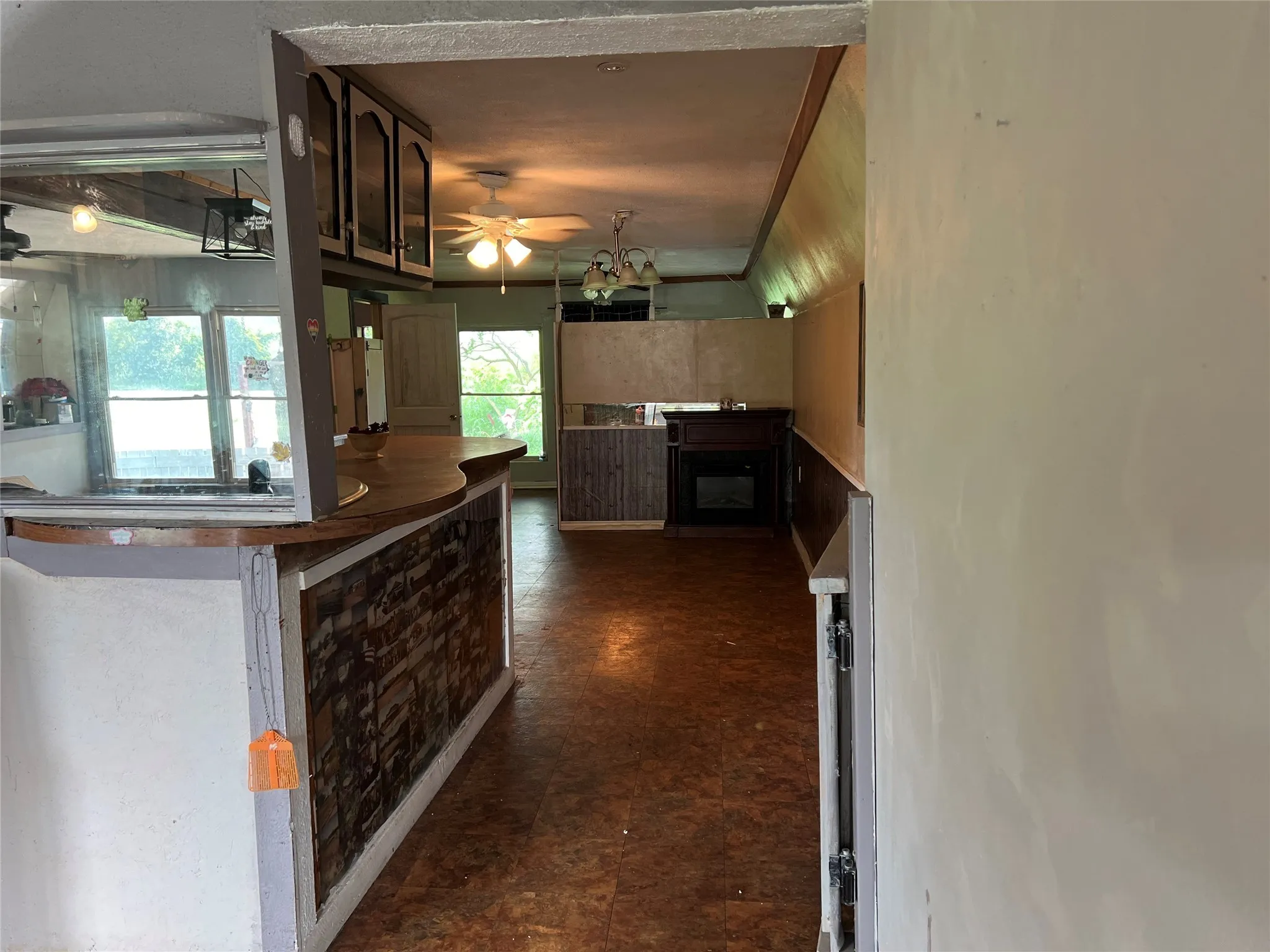 Kitchen featuring a ceiling fan, dark floors, and a fireplace