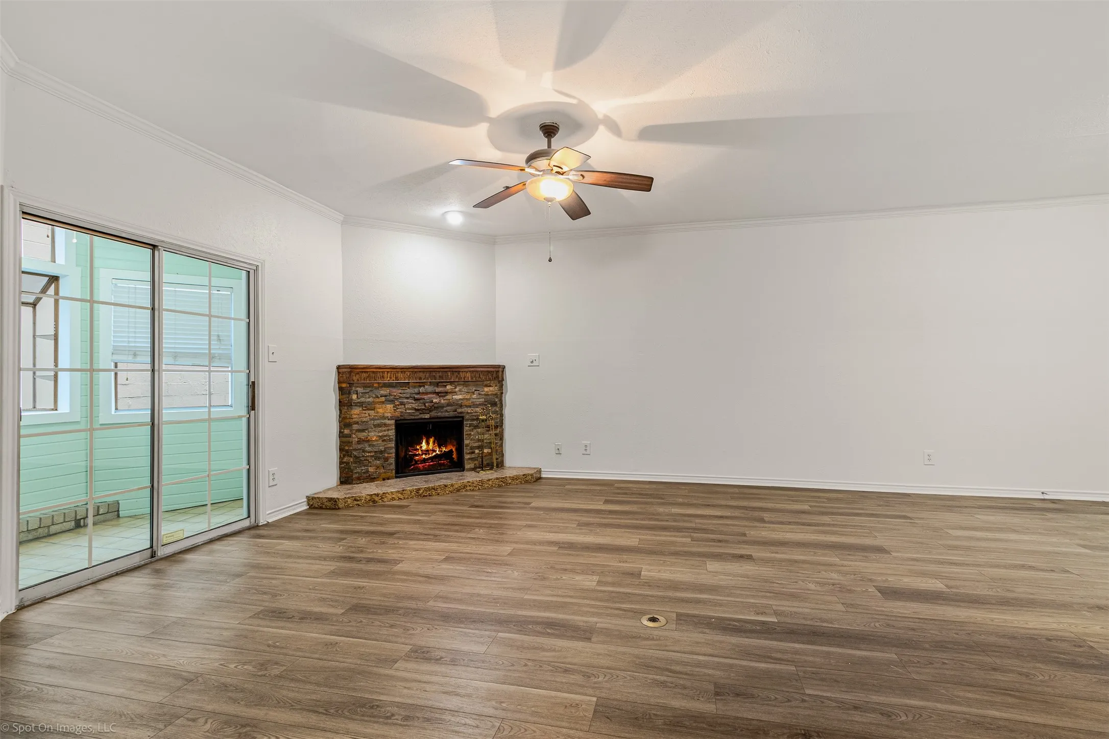 living room with wood finished floors, a fireplace, baseboards, ceiling fan, and ornamental molding