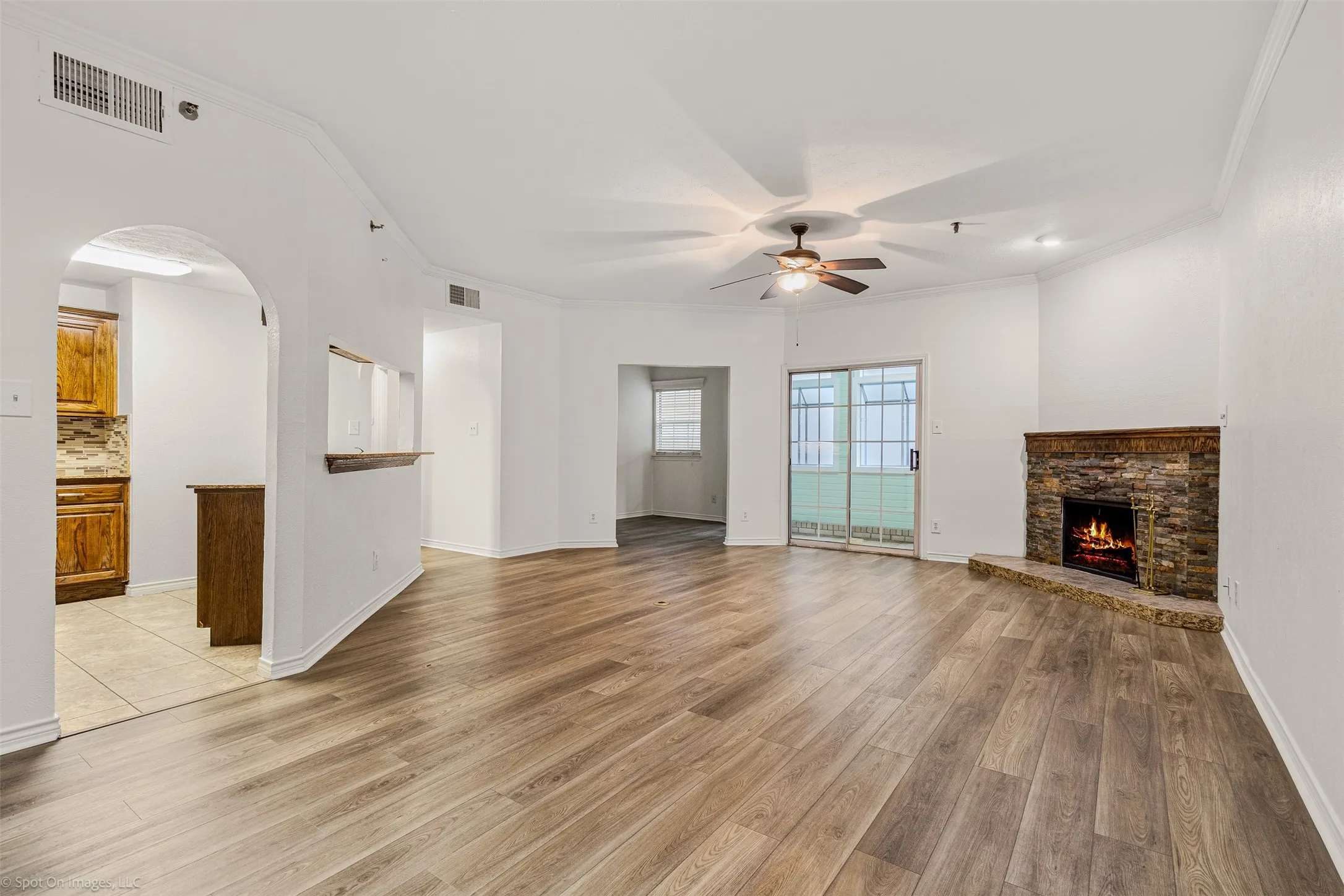 living room with light wood-type flooring, visible vents, a ceiling fan, and ornamental molding