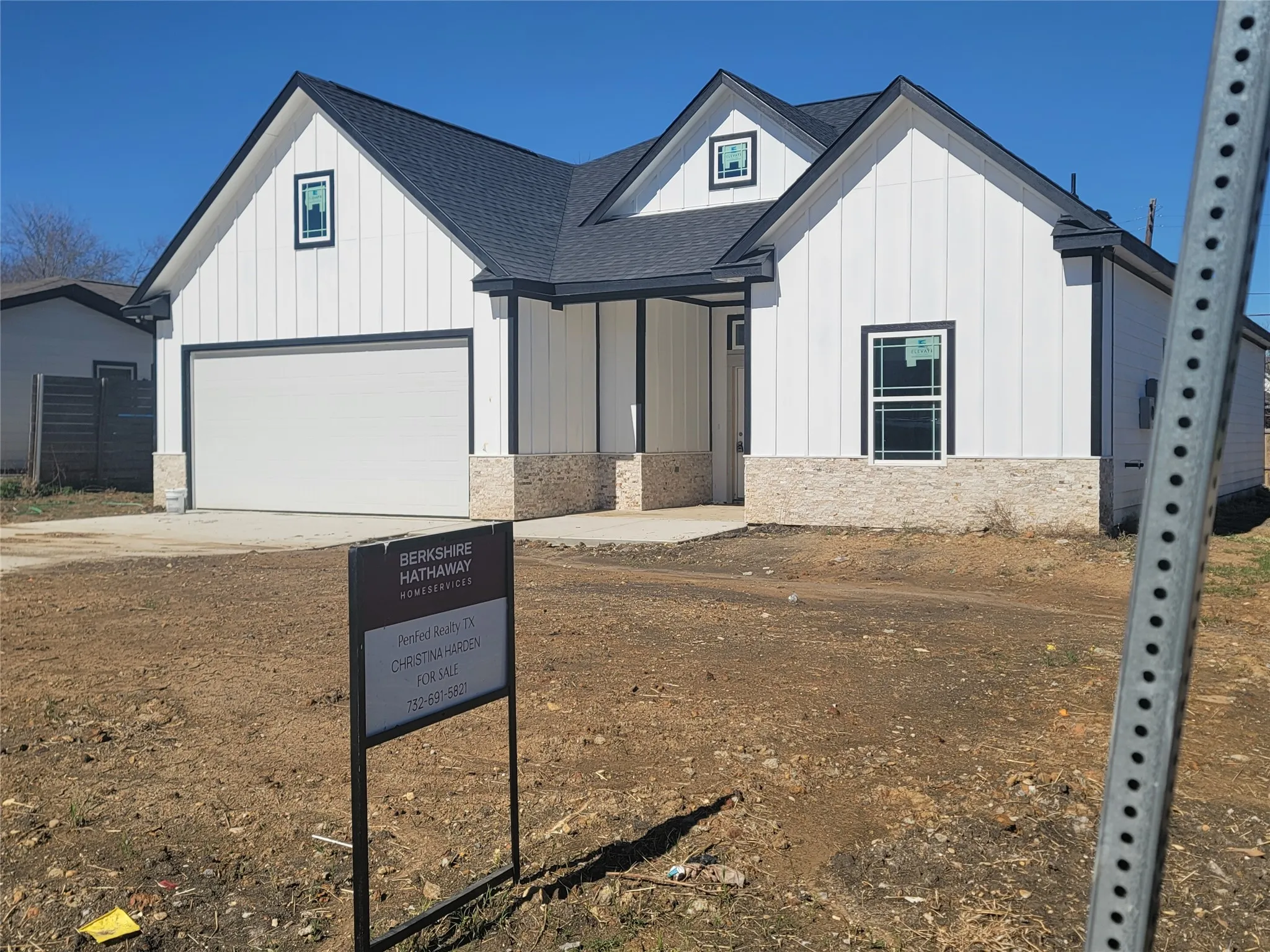 View of front facade with board and batten siding, concrete driveway, roof with shingles, and a porch