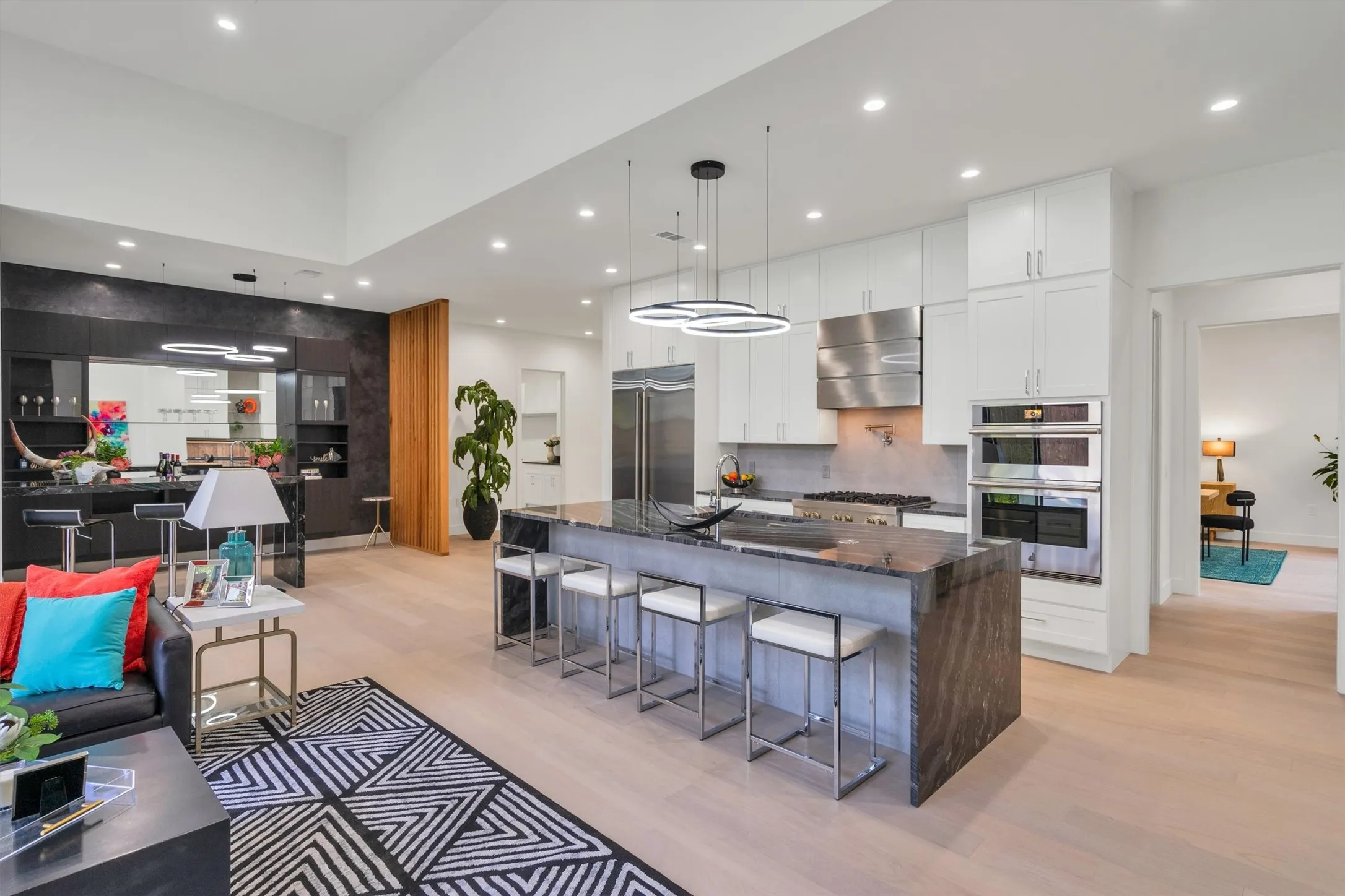 Kitchen featuring appliances with stainless steel finishes, wall chimney range hood, light wood-style flooring, backsplash, and white cabinets