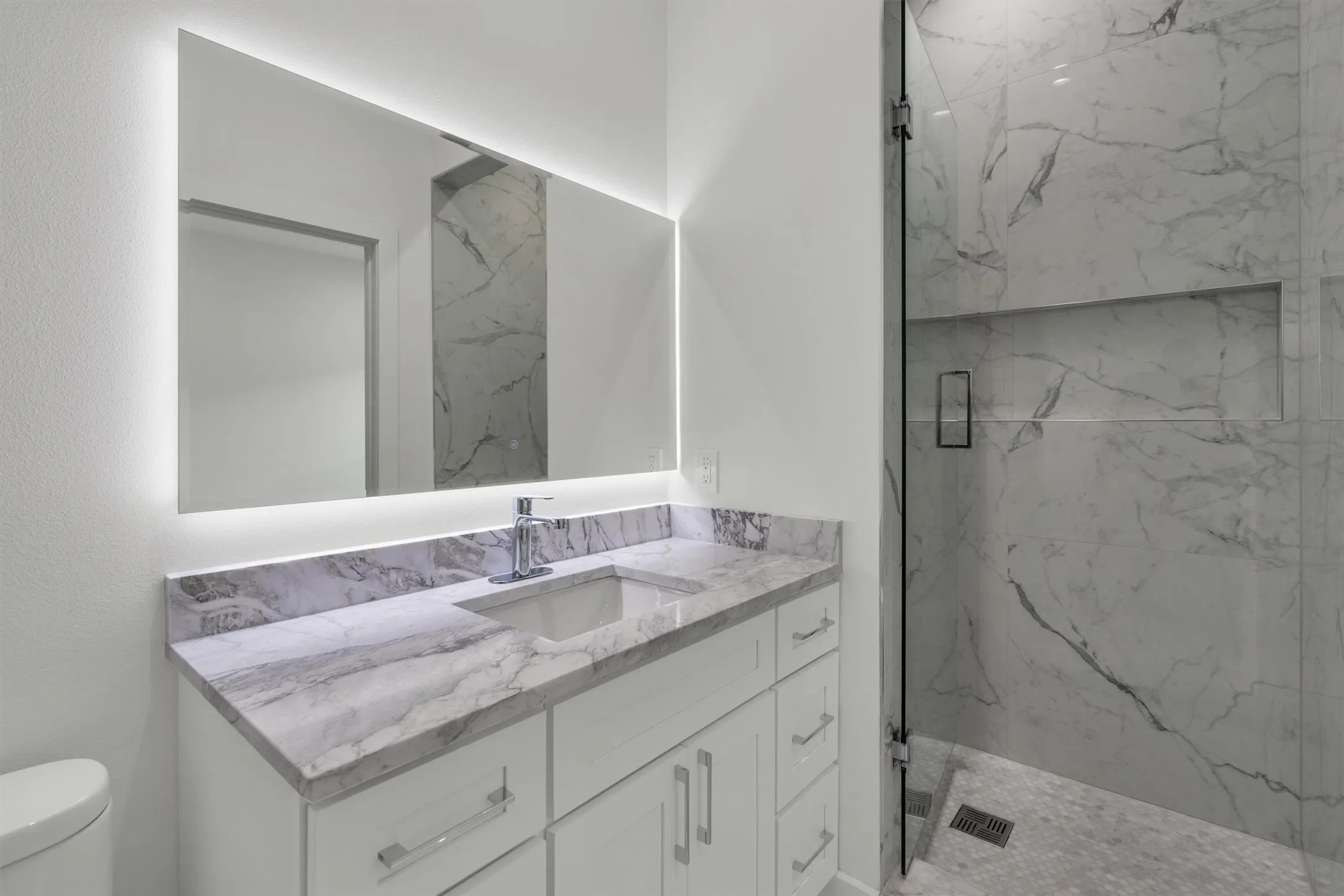 Bathroom featuring a marble finish shower, toilet, and vanity