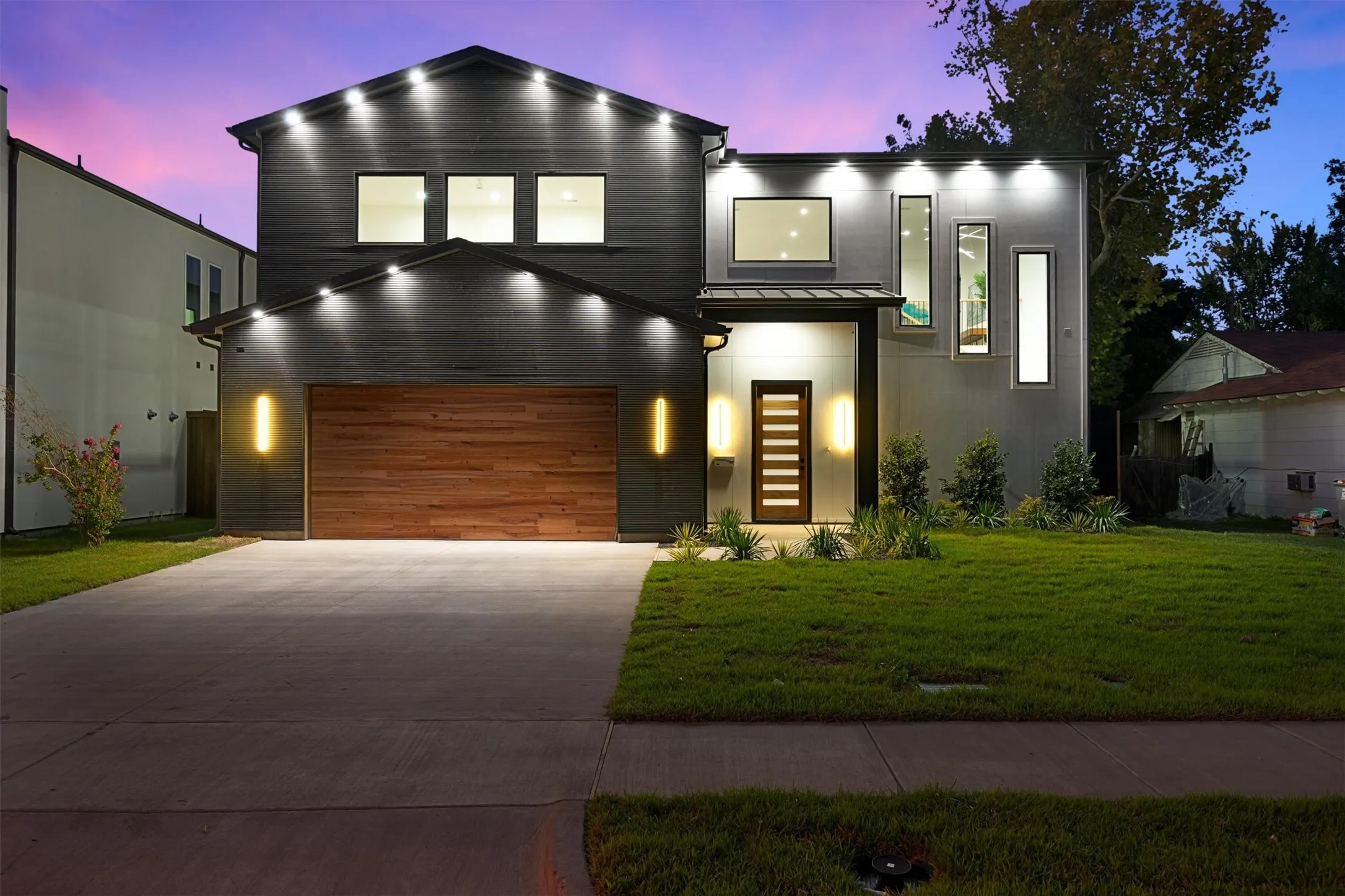 Contemporary home featuring driveway, a yard, a garage, a standing seam roof, and metal roof