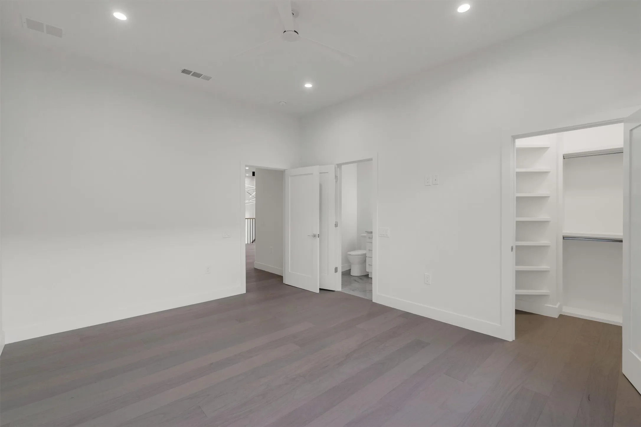 Unfurnished bedroom with a walk in closet, wood finished floors, recessed lighting, and baseboards