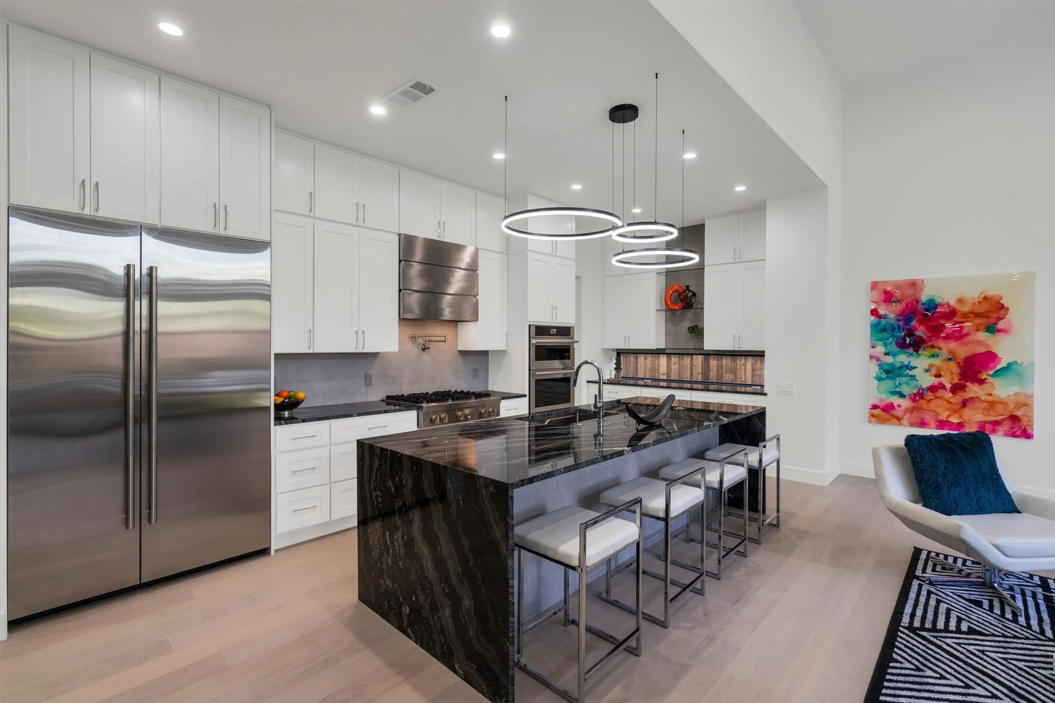 Kitchen featuring stainless steel appliances, extractor fan, light wood-style floors, backsplash, and recessed lighting