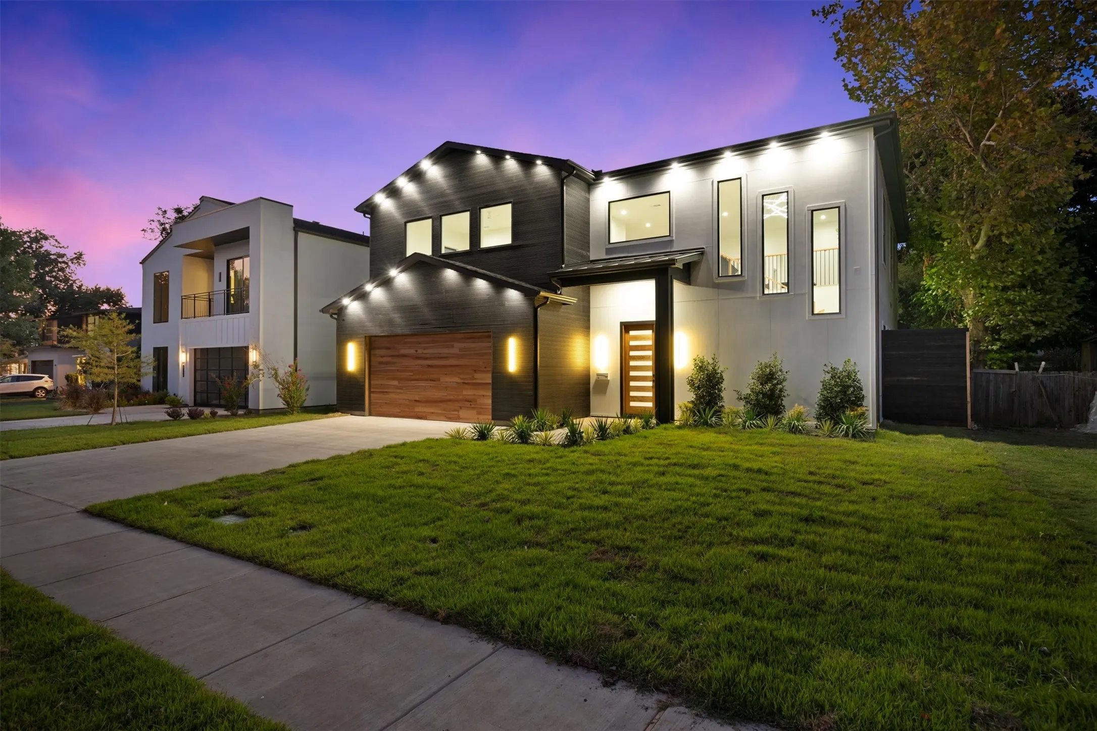 Modern home with driveway, an attached garage, and a lawn