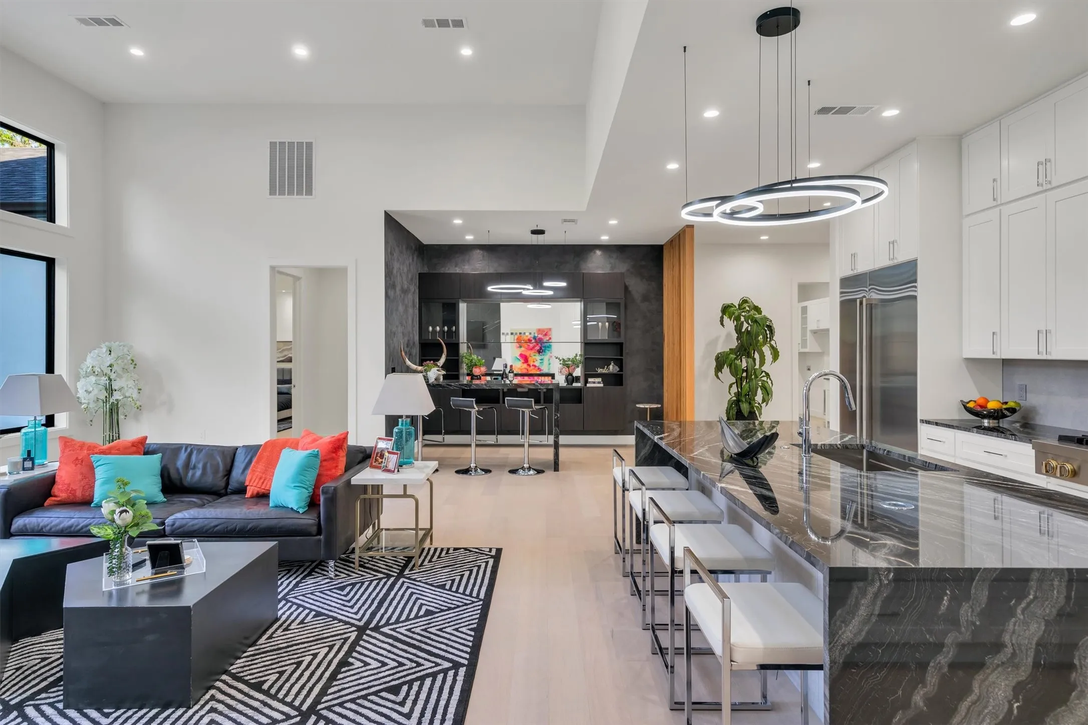 Living area with a towering ceiling, light wood-style flooring, and recessed lighting