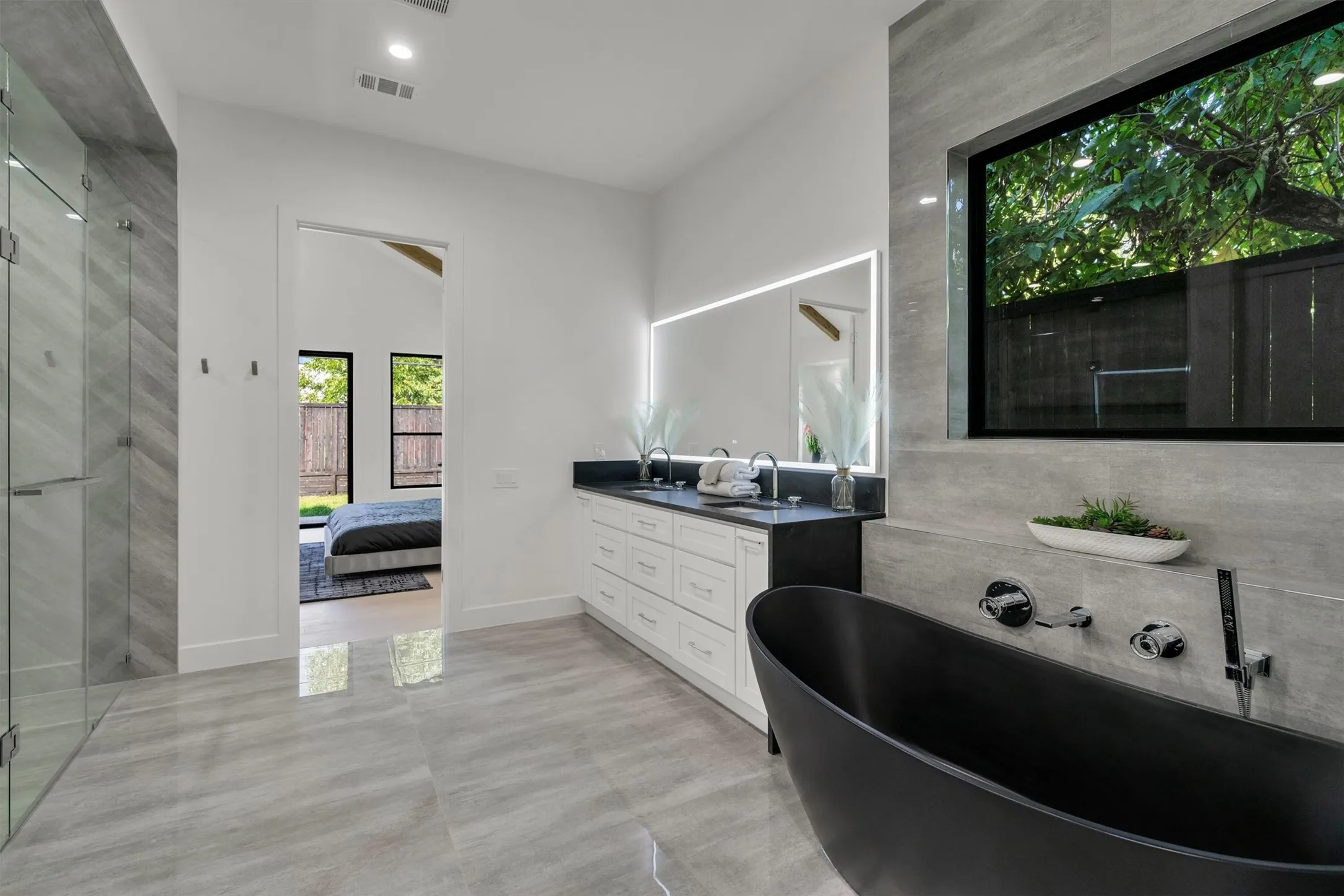 Full bathroom with double vanity, ensuite bath, a freestanding tub, and lofted ceiling